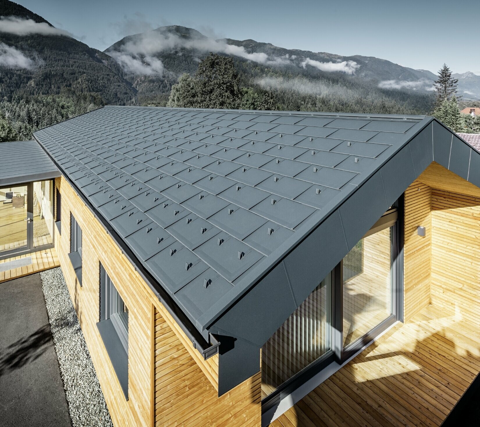 Budova s lehkou hliníkovou střechou, dřevěnou fasádou a prosklenou terasou