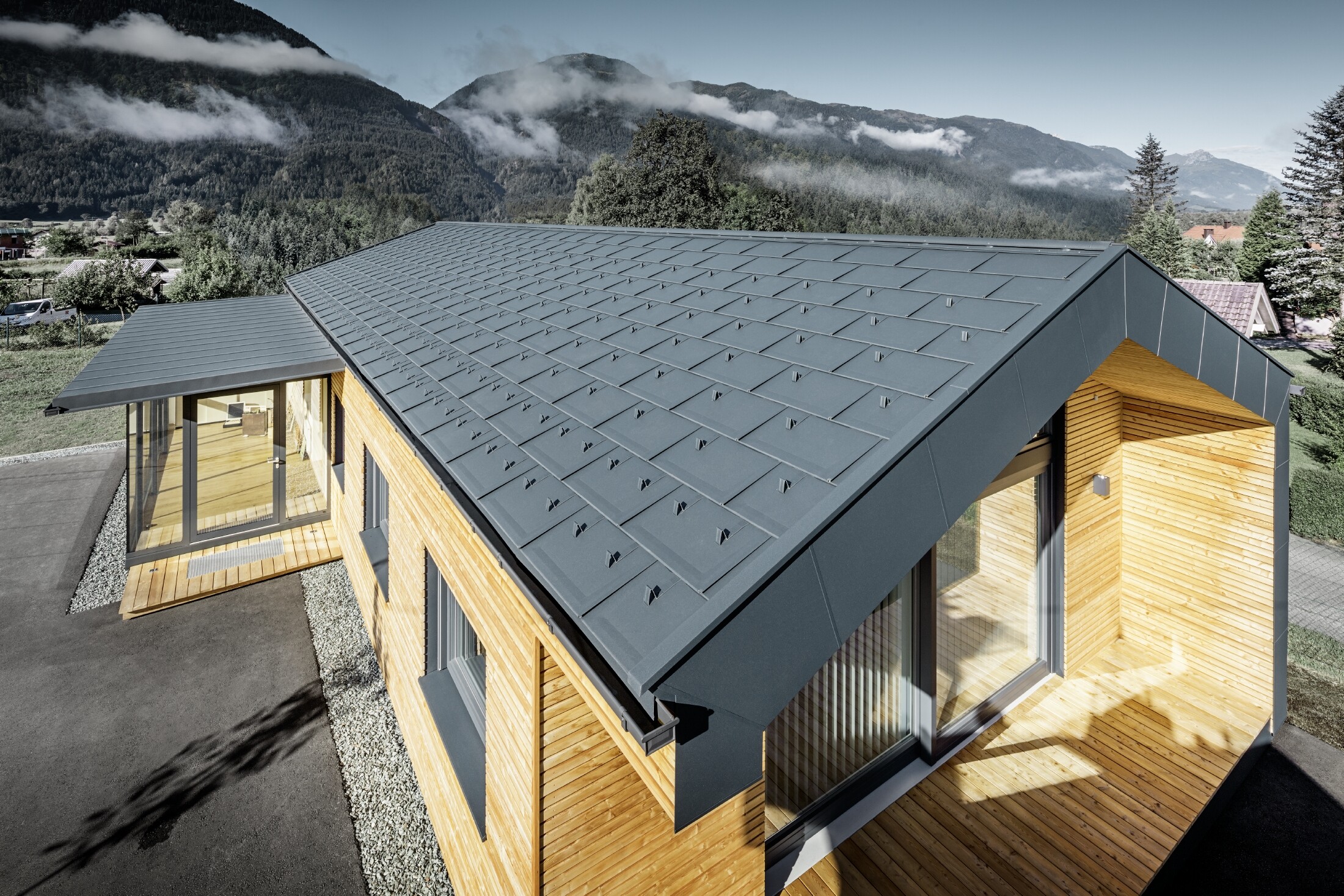 Budova s lehkou hliníkovou střechou, dřevěnou fasádou a prosklenou terasou