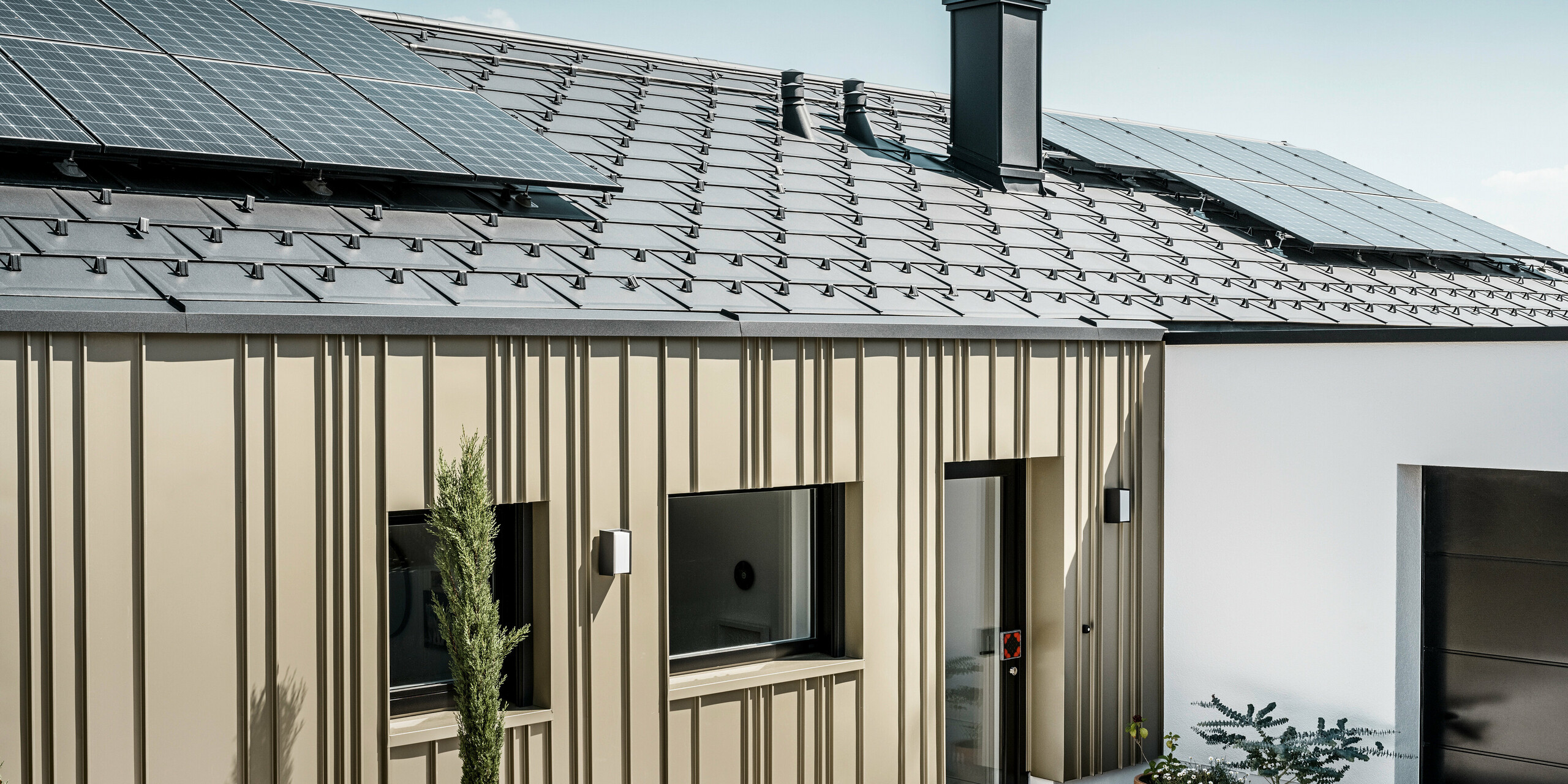 Ein Neubau in Bad Münstereifel wurde eingedeckt mit der PREFA Dachplatte R.16 in anthrazit. Auf dem Dach befindet sich eine Photovoltaik-Anlage. Die Winkelfalzfassade besteht aus Falzonal in lichtbronze.