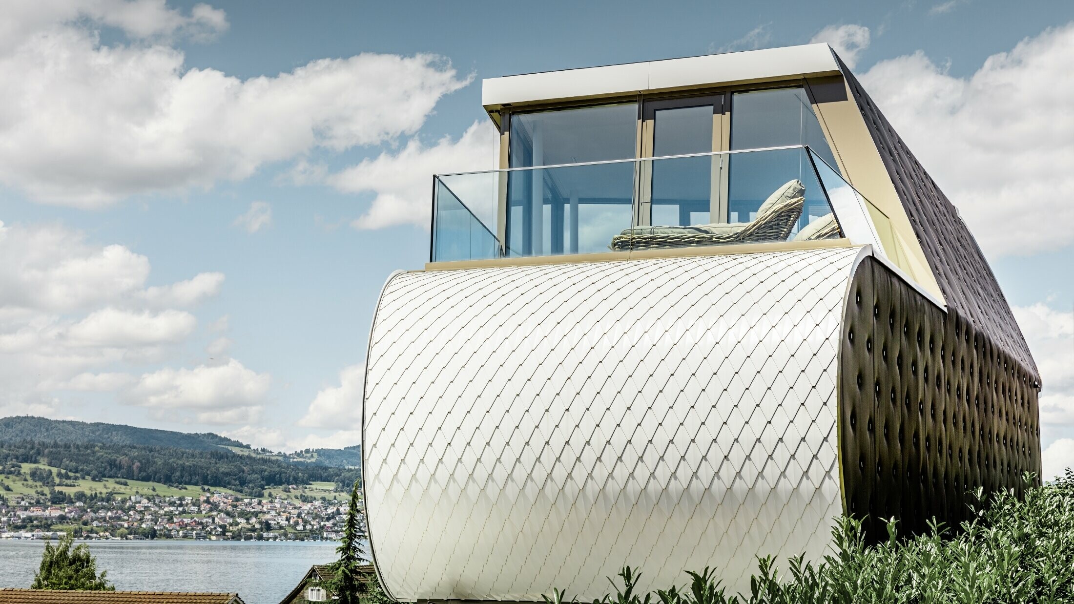 Boční pohled na velkolepý Flexhouse, navržený architektem Camenzindem; Můžete vidět jednu ze zakřivených vnějších stěn, která je obložena věžovkou od PREFA v barvě čistě bílé.