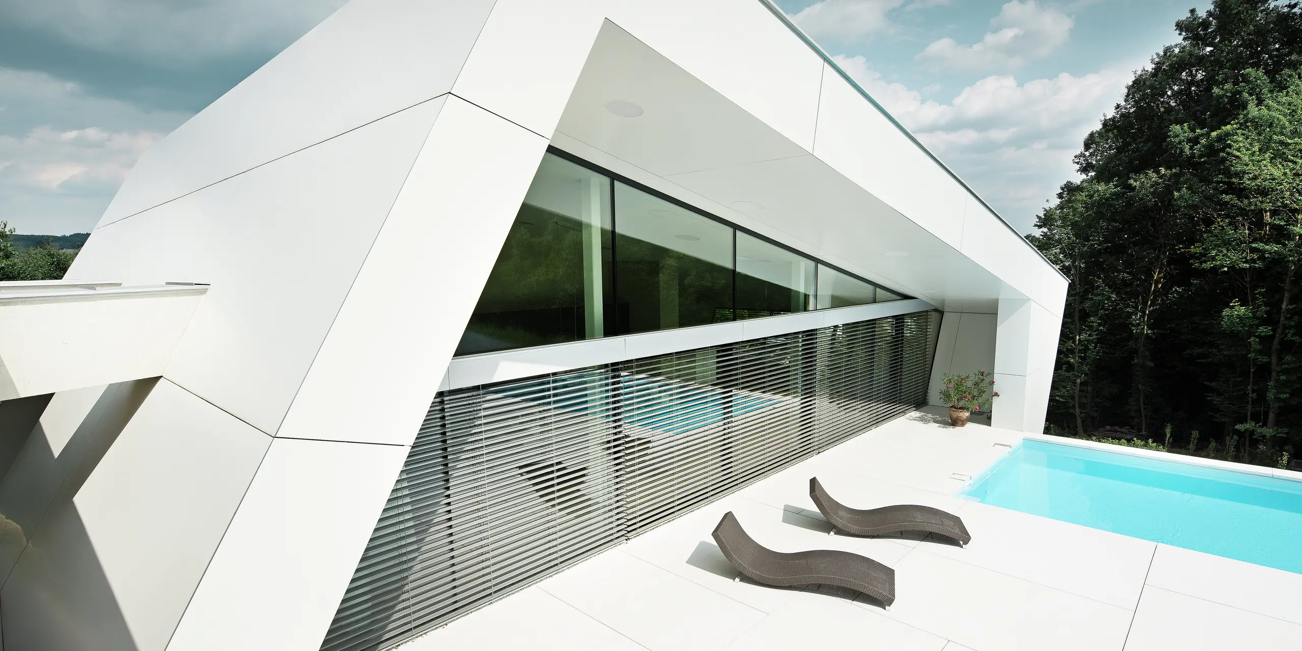 Die elegante Poolterrasse wird von einer geradlinigen PREFA Fassade in P.10 Reinweiß eingefasst. Die Aluminium Verbundplatten sorgen nicht nur für eine moderne Optik, sondern auch für langlebigen Schutz in allen Witterungslagen.