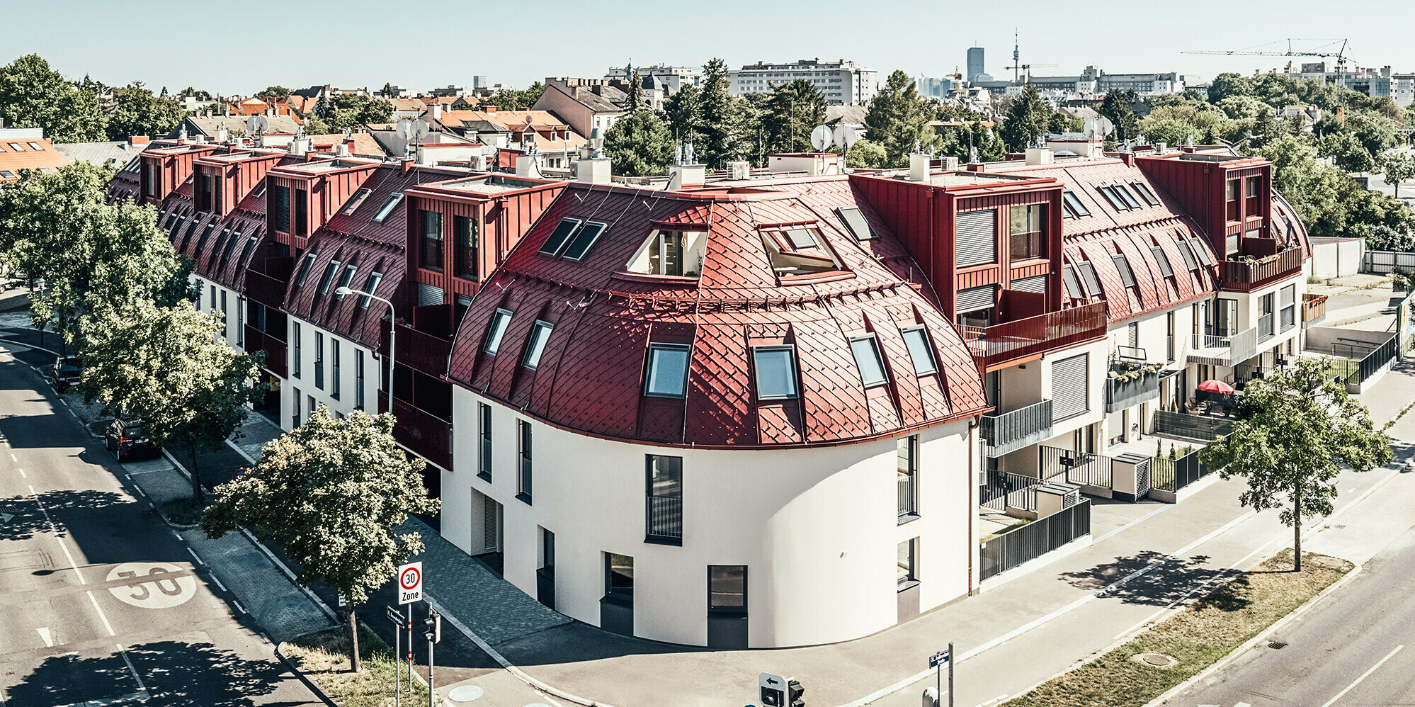 Pohled z ulice na rezidenční komplex Schöneck se zaoblenou střechou navrženou architekty schneider+schumacher