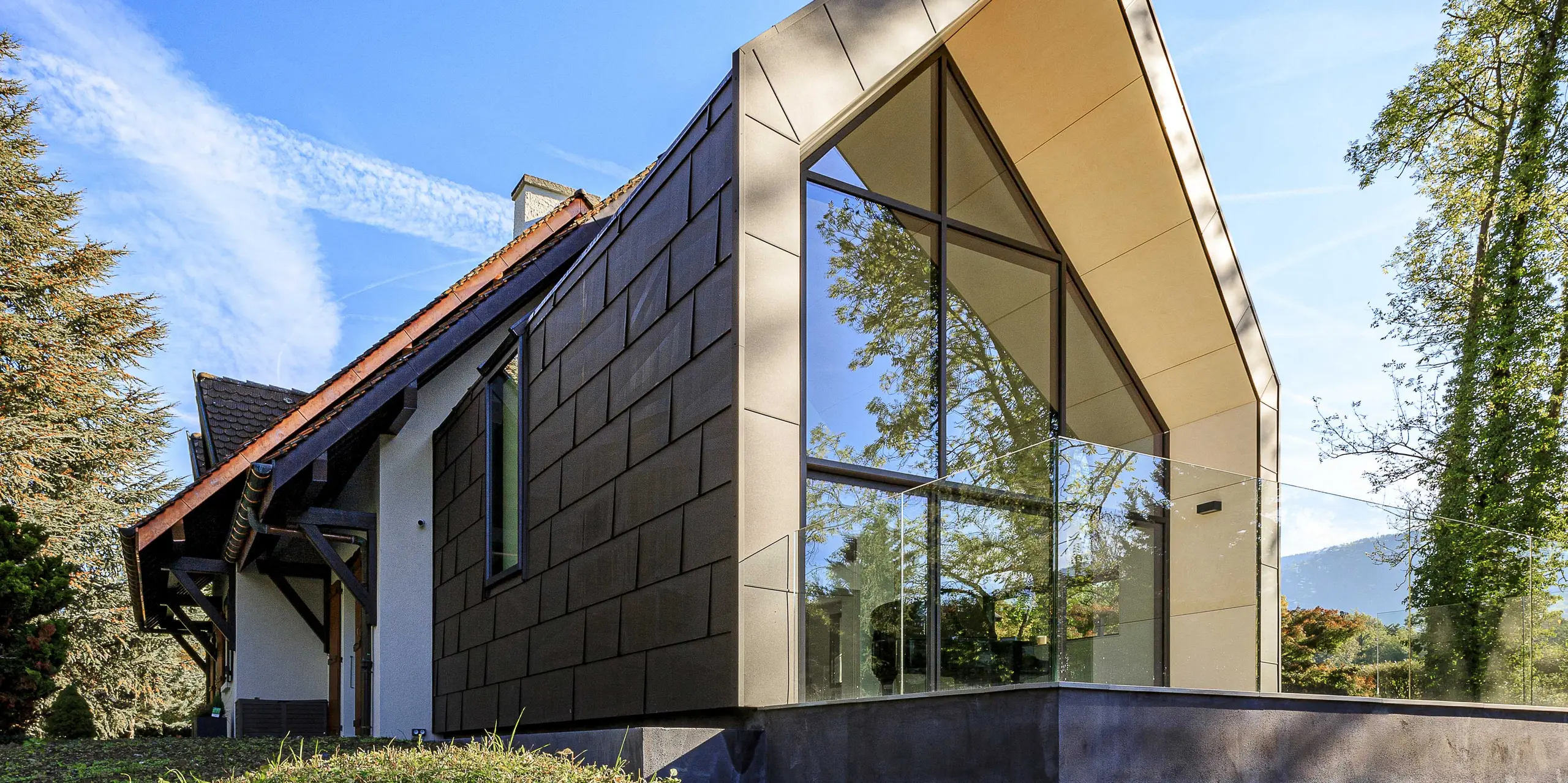 PREFA střešní a fasádní panely FX.12 v barvě P.10 tmavě hnědé jako kontrastní designový prvek na přístavbě rodinného domu v Lully