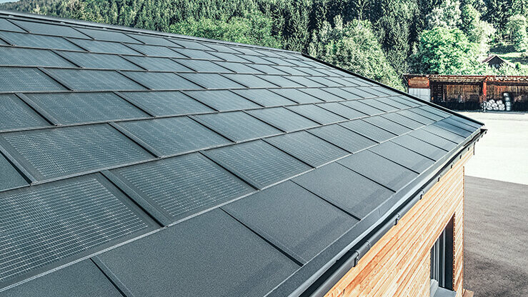 Velká verze integrovaného solárního panelu SDP v kombinaci se střešním panelem R.16 a odvodňovacím systémem v barvě P.10 černé. Fasáda je z modřínového dřeva.