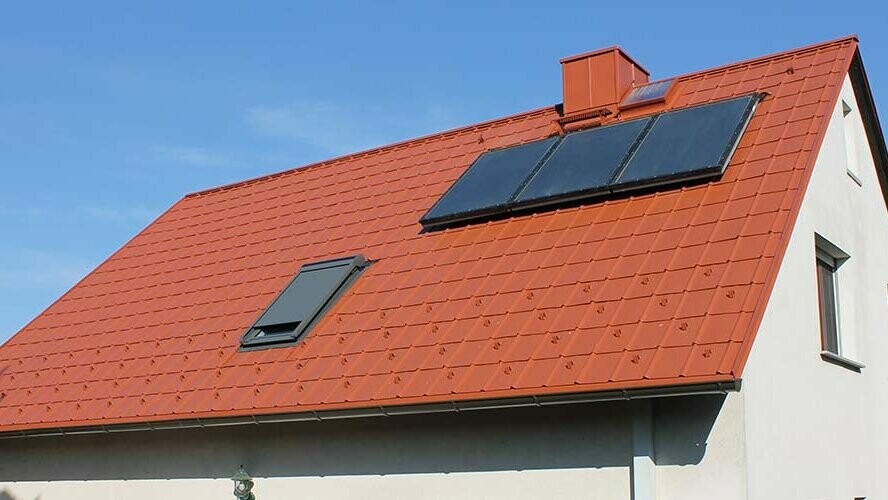 Rodinný dům se sedlovou střechou pokrytou PREFA falcovanými střešními taškami v cihlově červené barvě. Plocha střechy včetně solárního zařízení a střešního okna
