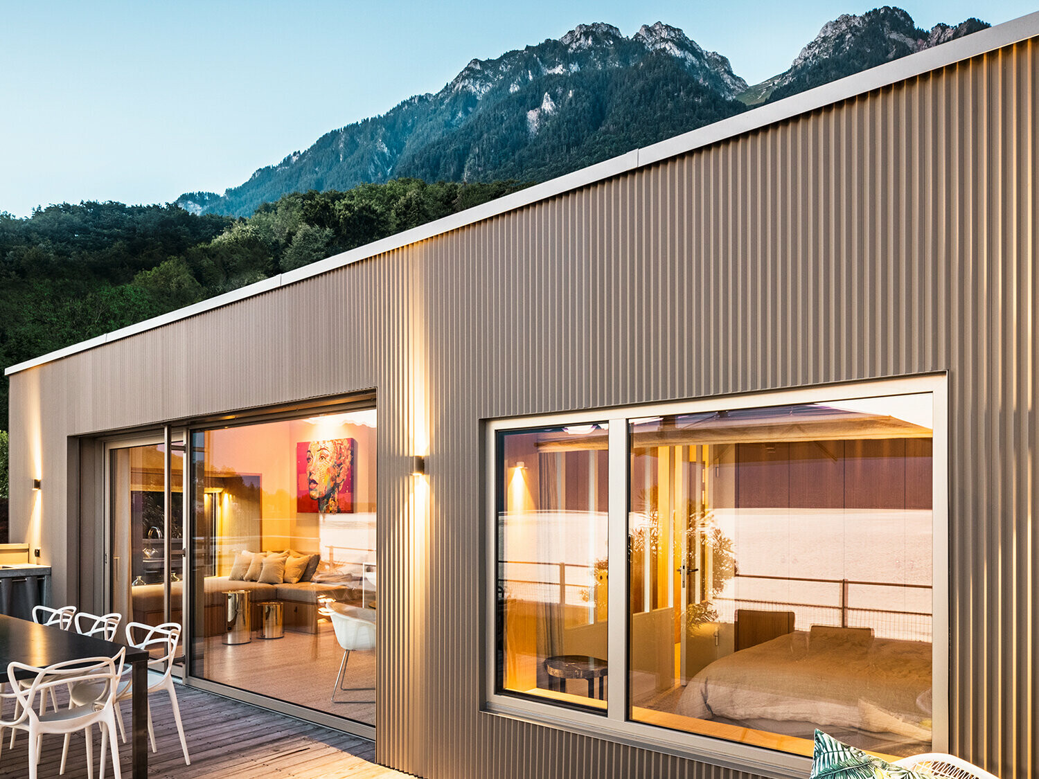 Pohled na terasu a část interiéru budovy večer.