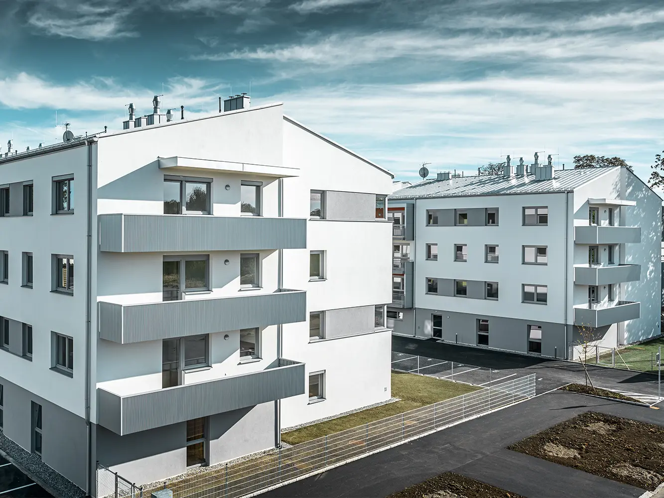 Moderní bytový komplex s bílou fasádou a balkony s PREFFA Zackenprofilem v barvě stříbrná metalíza