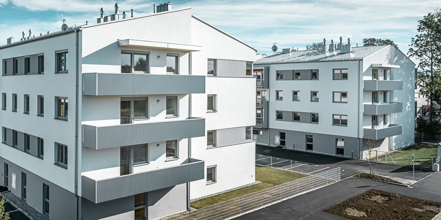 Moderní bytový komplex s bílou fasádou a balkony s PREFFA Zackenprofilem v barvě stříbrná metalíza