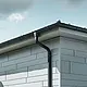 Pohled na střechu domu se střešním žlabem PREFA, kulatým kotlíkem a kruhovým svodem v antracitové barvě a s fasádou z lamel PREFA Siding.X v barvě patina šedá