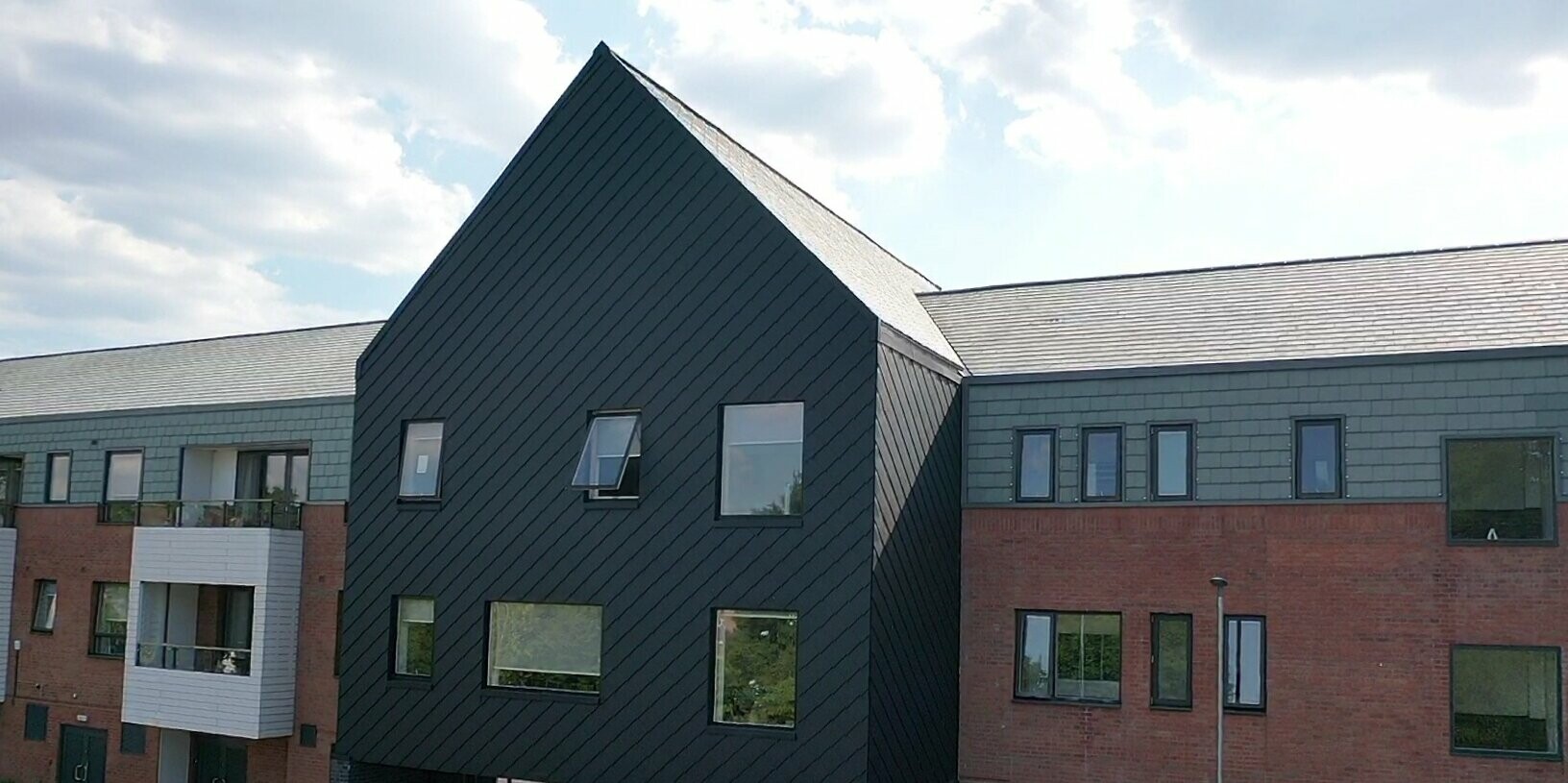 Budova hlavního vchodu do budovy j opláštěná do hliníkových šablon 29 × 29 v barvě P.10 černé od PREFA.