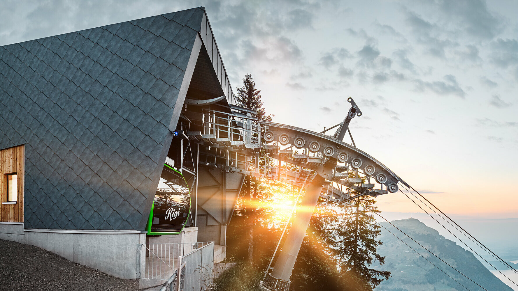 Stanice kabinové lanovky ve Švýcarsku se střechou a fasádou PREFA při západu slunce.