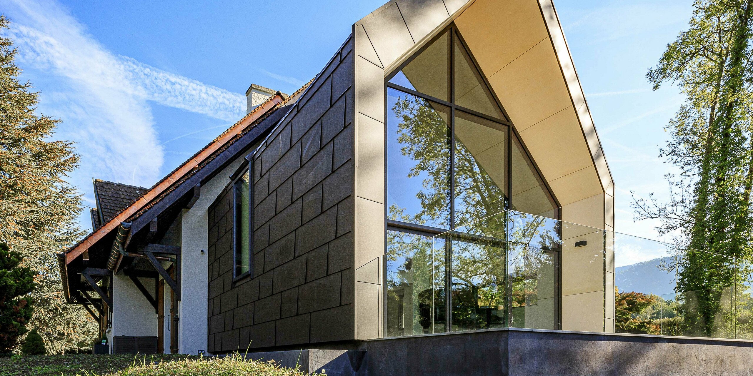 PREFA střešní a fasádní panely FX.12 v barvě P.10 tmavě hnědé jako kontrastní designový prvek na přístavbě rodinného domu v Lully