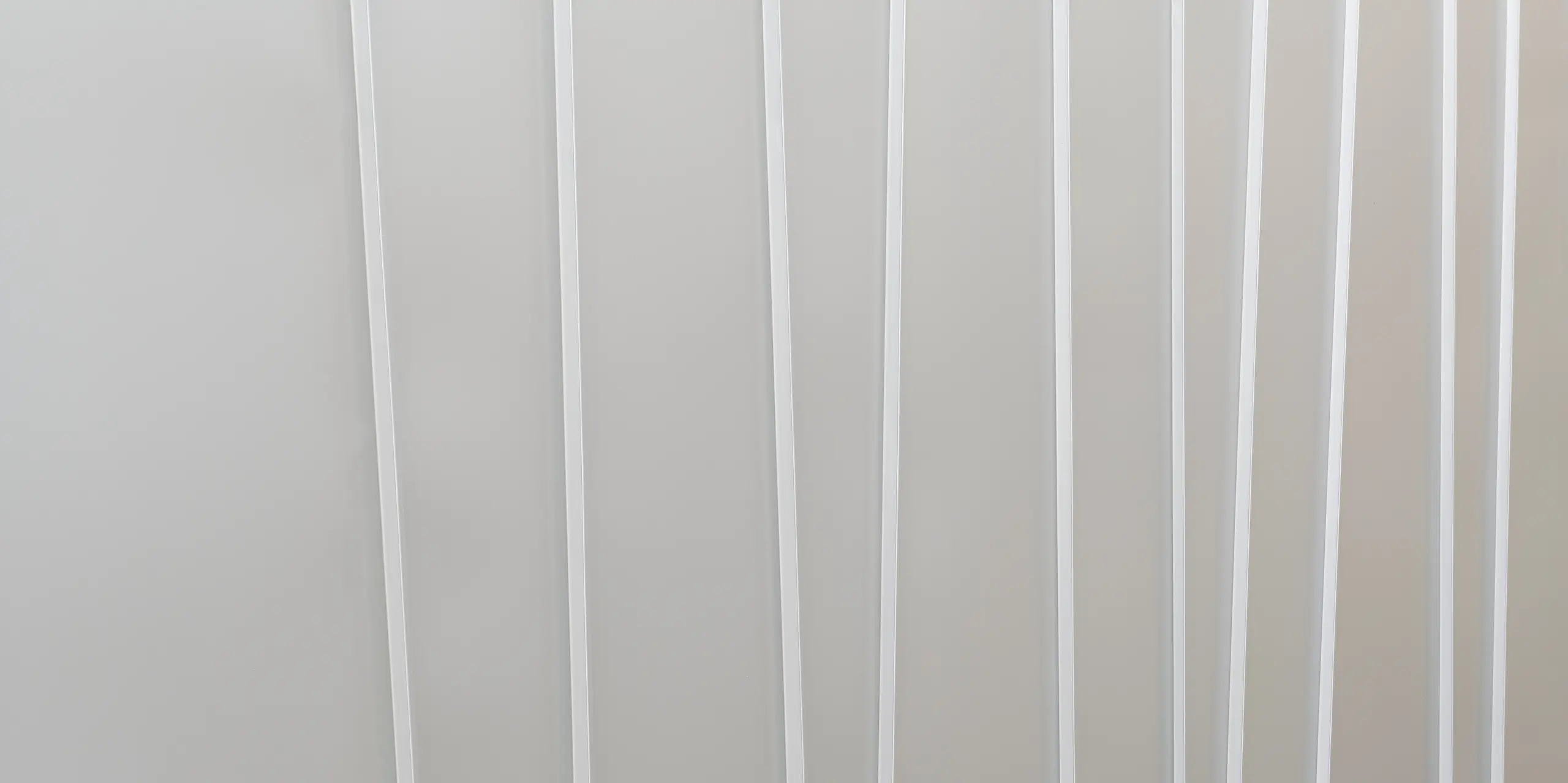 Detailní záběr na moderní fasádní systém z PREFALZ v barvě P.10 světle šedé barvě v různých šířkách pásů. Čistá a minimalistická textura navozuje pocit pořádku a současného designu.