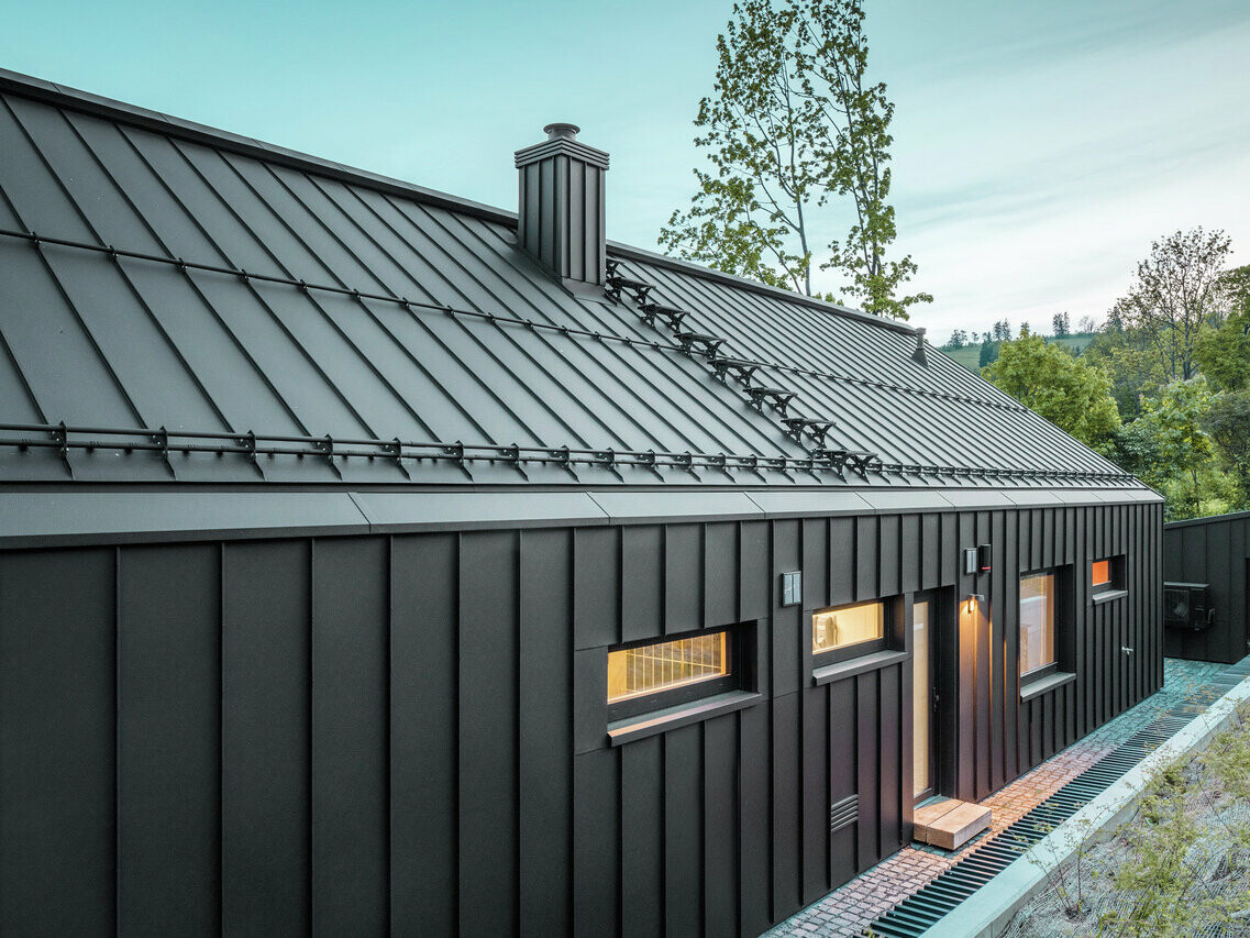Střecha a fasáda z PREFALZ v barvě P.10 černé. Střecha má také protisněhové prvky PREFA.