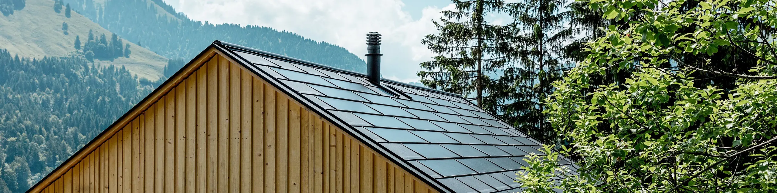 Haus Immi, zasazený mezi zelené koruny stromů a působivou horskou kulisou, se prezentuje jako moderní útočiště v alpské vesničce Ebnit. Přírodní fasáda z bílé jedle se setkává s elegantní solární střechou PREFA v černé barvě P.10. Integrované střešní solární panely a střešní panely R.16 kombinují udržitelnou výrobu energie, robustní ochranu před povětrnostními vlivy a čistý, harmonicky integrovaný architektonický design, který splňuje nejvyšší standardy.