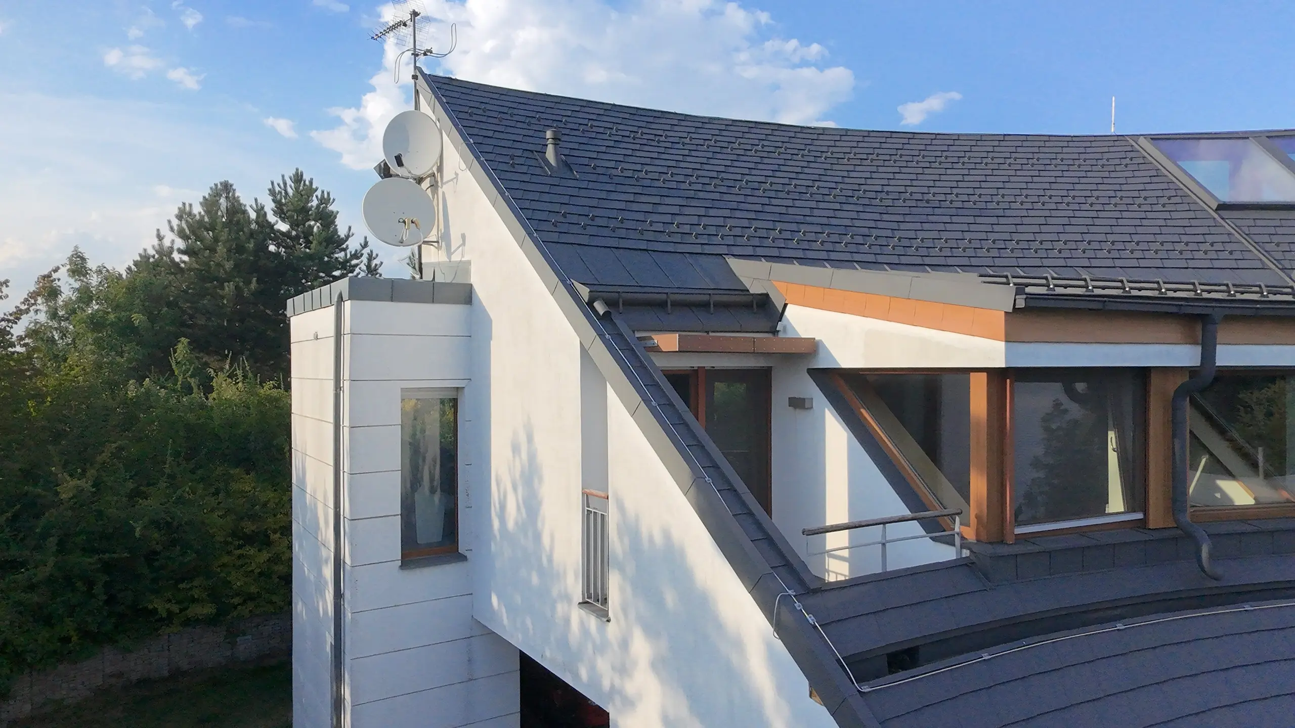 Boční pohled na nároží rodinné vily s pultovým vikýřem a materiály PREFA