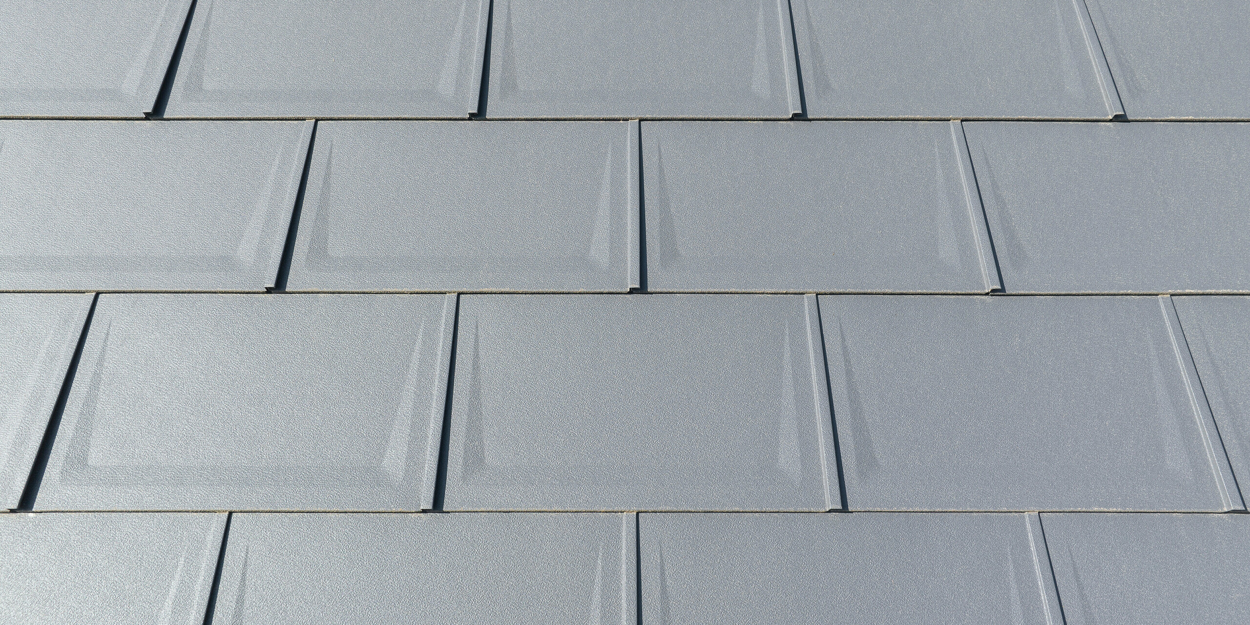 Pohled zblízka na střešní panel R.16 v barvě P.10 tmavě šedé v povrchové úpravě stucco namontovaný v pravidelných řadách