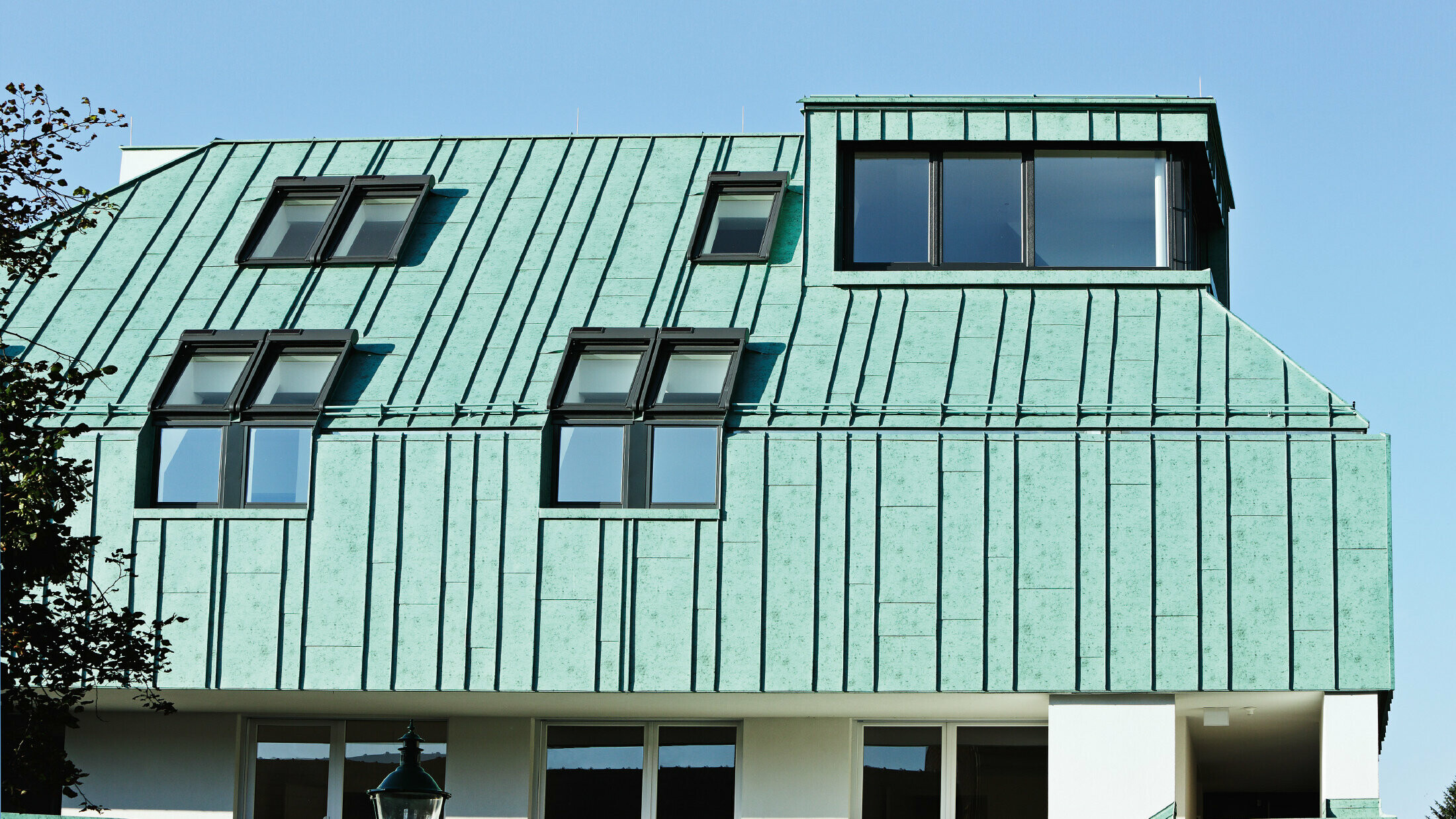 Řešení střechy a fasády se systémem PREFA v barvě zelená patina a s nestejně širokými pásy