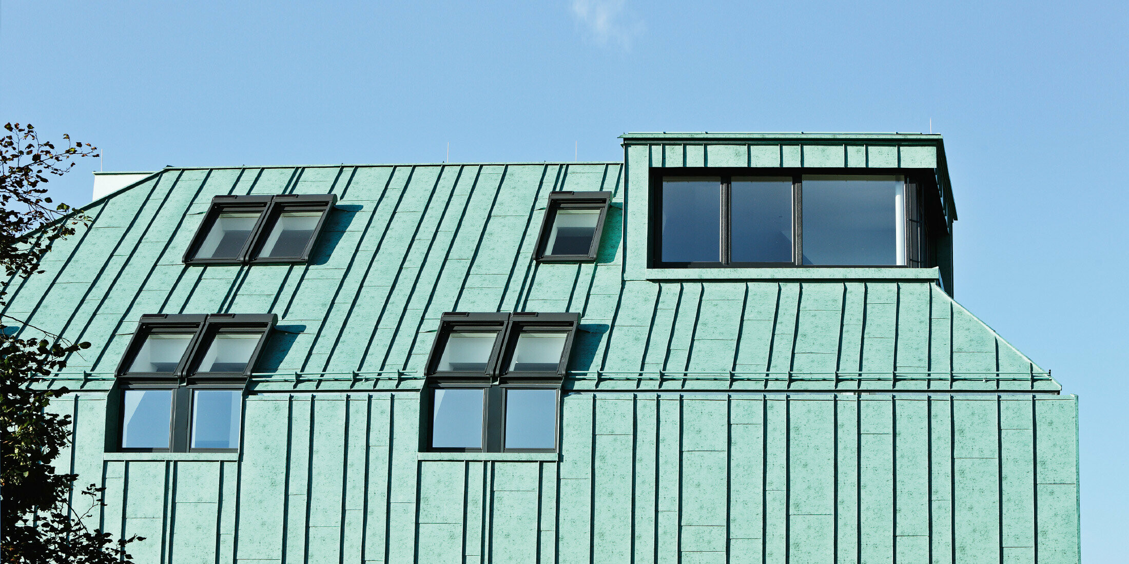 Řešení střechy a fasády se systémem PREFA v barvě zelená patina a s nestejně širokými pásy