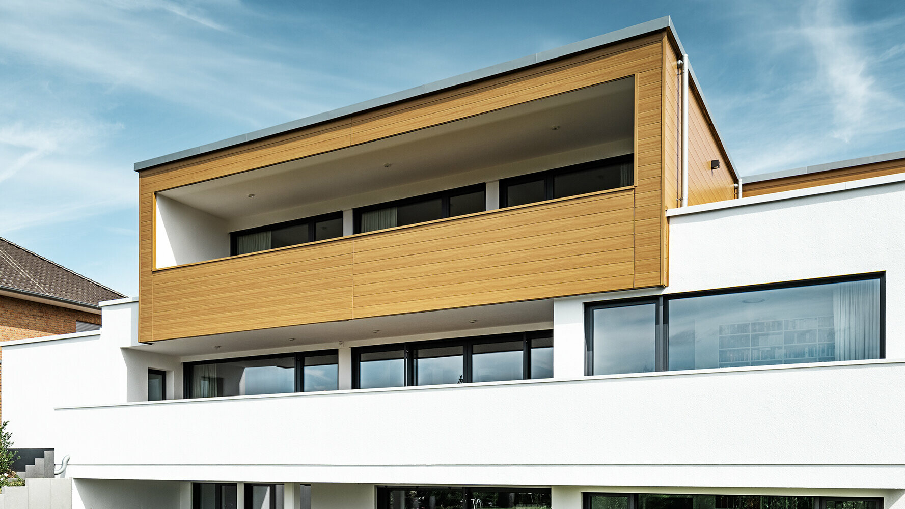 Moderní dům s arkýřem obloženým fasádními lamelami Siding PREFA v barvě šedého dubu.