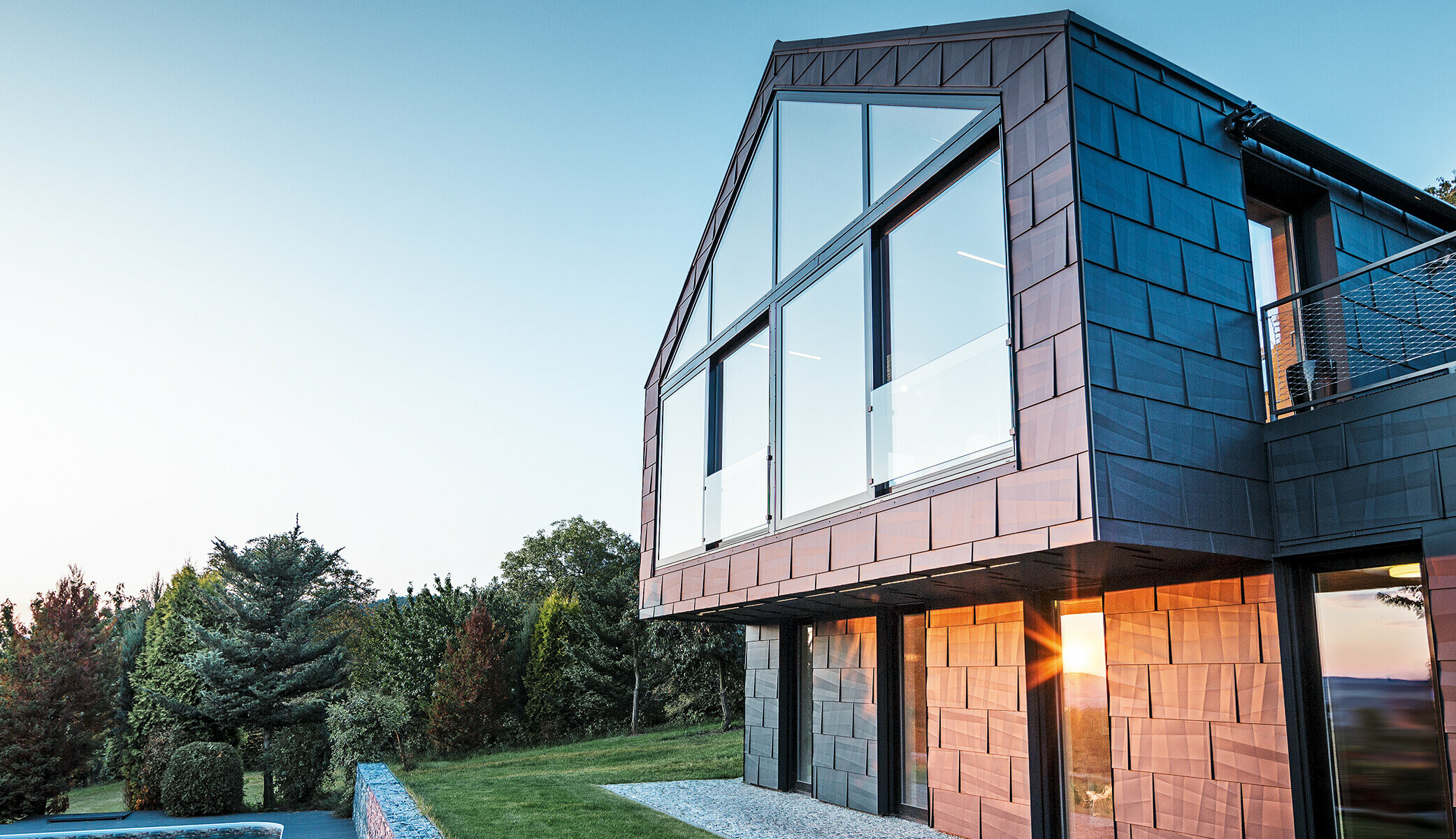 Modernes Einfamilienhaus ohne Dachvorsprung mit großen Fensterflächen und FX.12 Fassade in Anthrazit, bei Sonnenuntergang fotografiert.