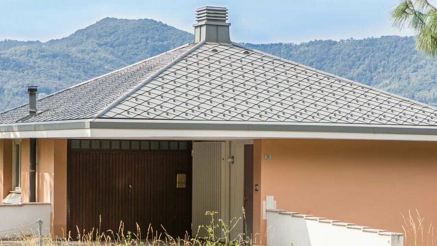 Oranžový obytný dům se stanovou střechou pokrytou PREFA falcovanými šablonami 29 × 29 světle šedé barvy P.10.