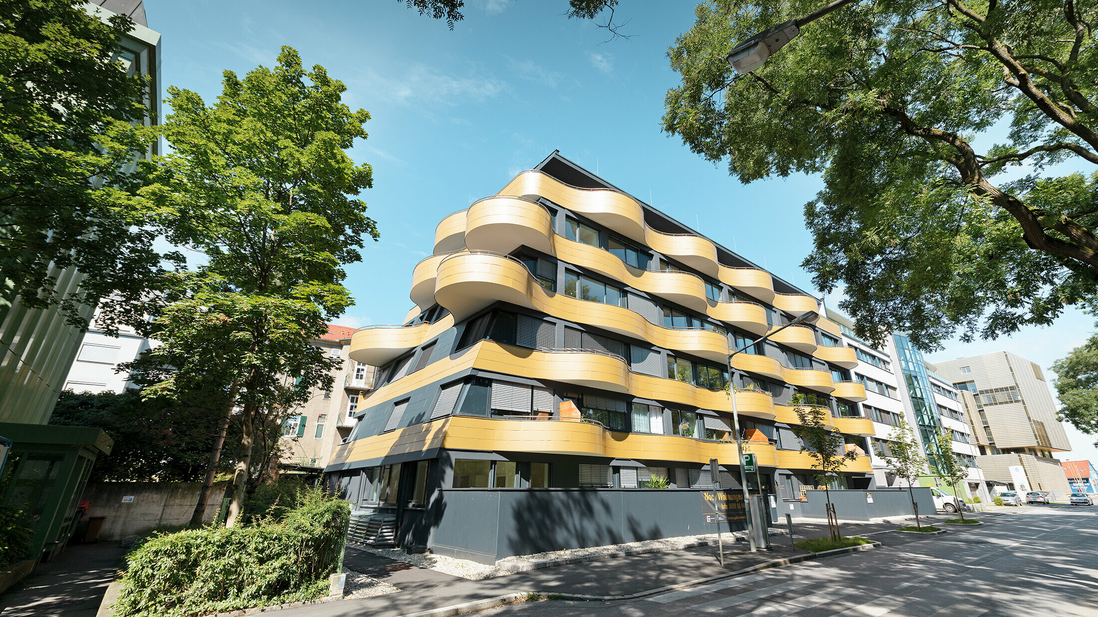 Obytný komplex "Golden Wave" neboli zlatá vlna v rakouském Grazu s hliníkovou kompozitní deskou PREFABOND ve zlaté barvě. Balkony zde byly zaobleny do vln.