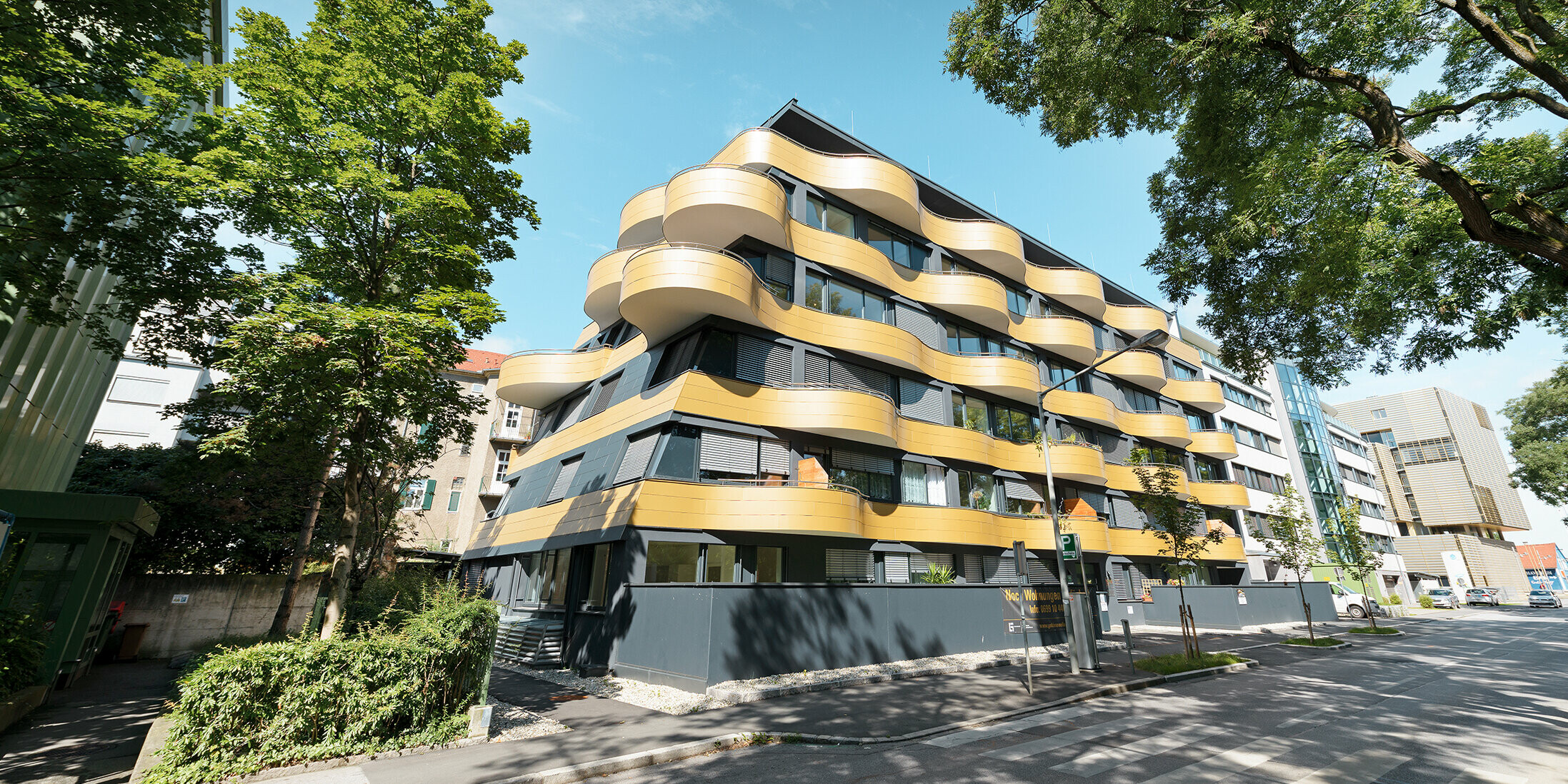 Obytný komplex "Golden Wave" neboli zlatá vlna v rakouském Grazu s hliníkovou kompozitní deskou PREFABOND ve zlaté barvě. Balkony zde byly zaobleny do vln.