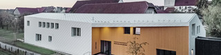 Pohled na budovu evangelické školy opláštěnou falcovanou a fasádní šablonou PREFA 44 × 44 