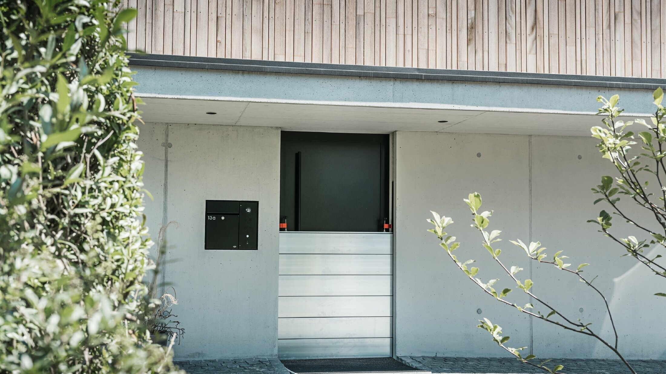 Před vstupními dveřmi rodinného domu s dřevěnou fasádou je instalována protipovodňová ochrana PREFA. 