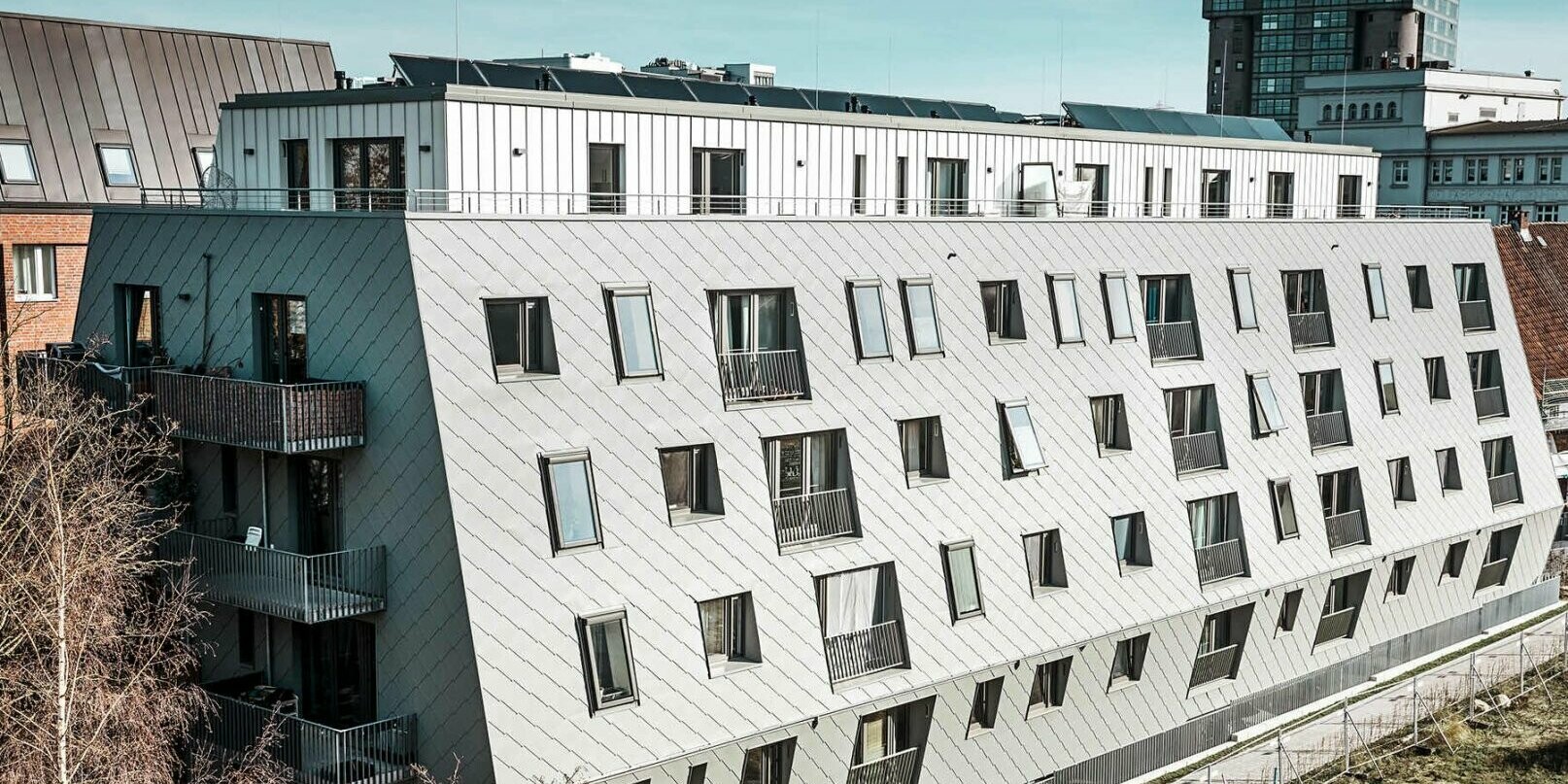 Na obrázku dům v přístavním městě Hamburg ve dne, který byl pokryt PREFA fasádními šablonami 44x44 a svitkovým plechem PREFALZ.