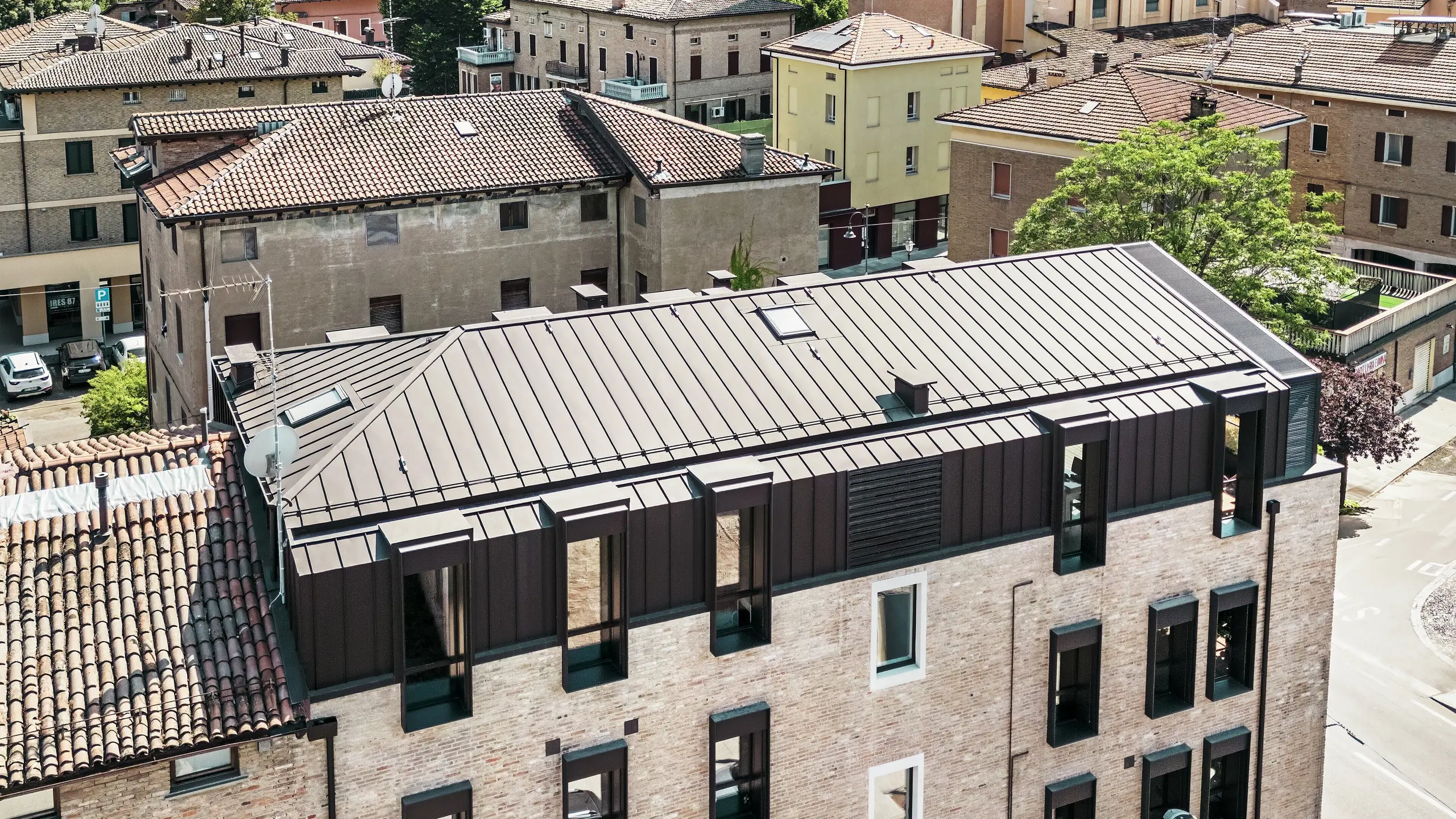 Modernizovaný cihlový dům v Itálii s hliníkovou střechou z drážkované krytiny PREFALZ v barvě P.10 oříškové – estetická kombinace tradiční cihlové architektury a moderního, odolného střešního řešení