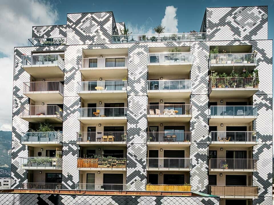 Čelní pohled na obytný dům Le Python v Grenoblu s mnoha balkony a hliníkovou fasádou od PREFA, fasádní šablony 20 x 20 vytvářejí vzor podobný hadovi s barvami antracit, světle šedá, přírodní hliník a metalická stříbrná
