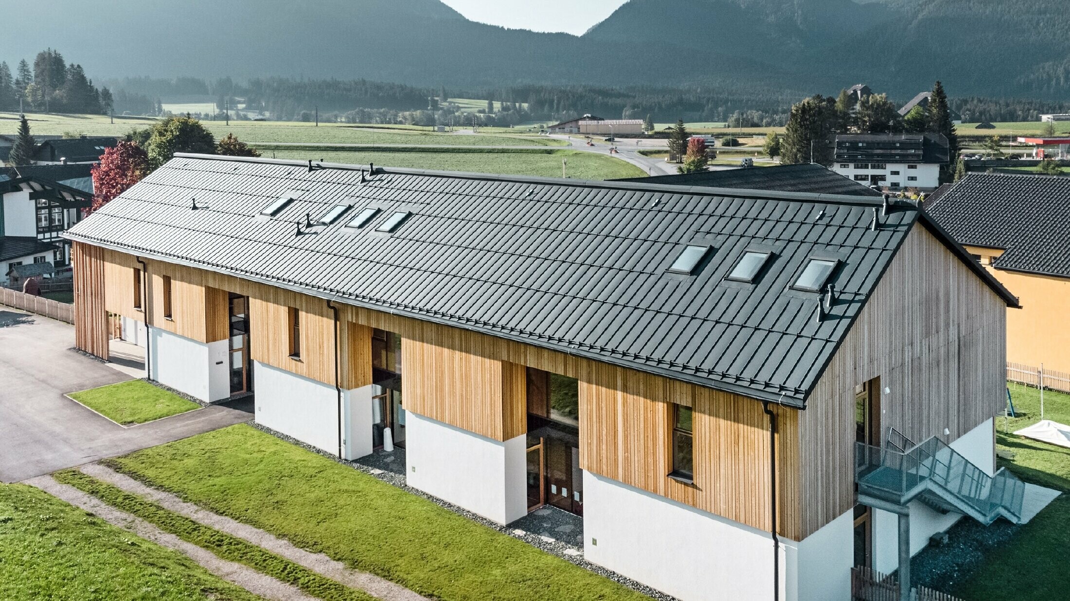 Bylinková mateřská školka v Bad Mitterndorfu s velkou střechou PREFALZ v provedení P.10 antracitová a dřevěná fasáda