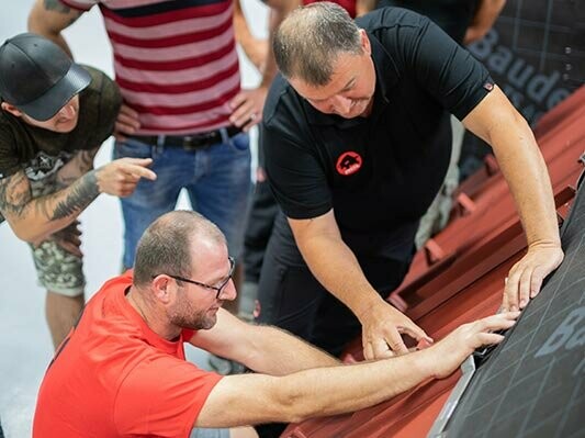 Instruktor pokládky PREFA předvádí účastníkovi PREFA Academy správnou pokládku produktů PREFA.