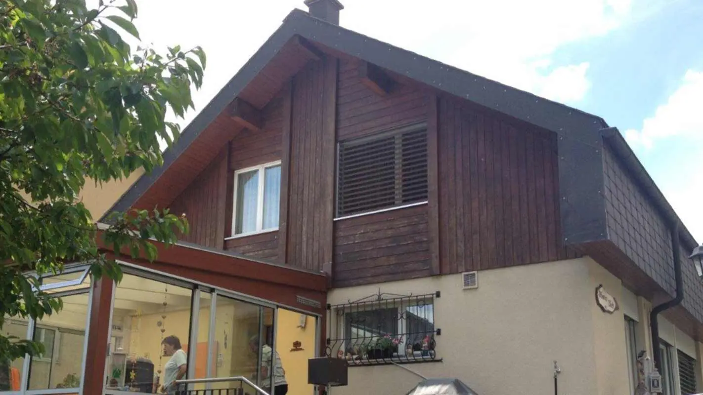 Dům před sanací fasády za použití PREFA Sidings s optikou dřeva, štít je v současné době obložen zvětralým dřevem
