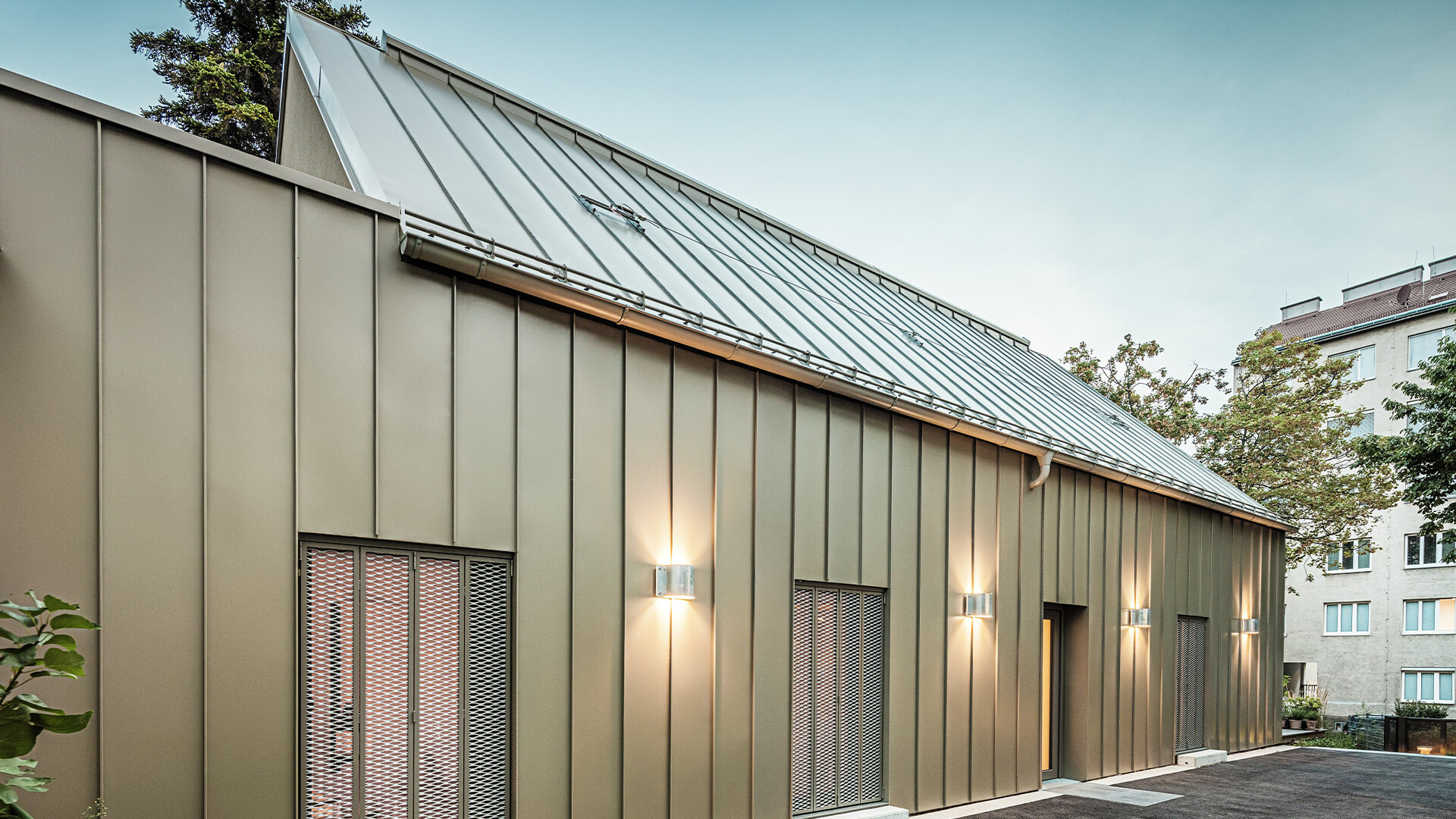 Detailní pohled na architektonický ateliér Comploj se střechnou a fasádou z drážkové krytiny PREFALZ v barvě P.10 prefa bronzové.