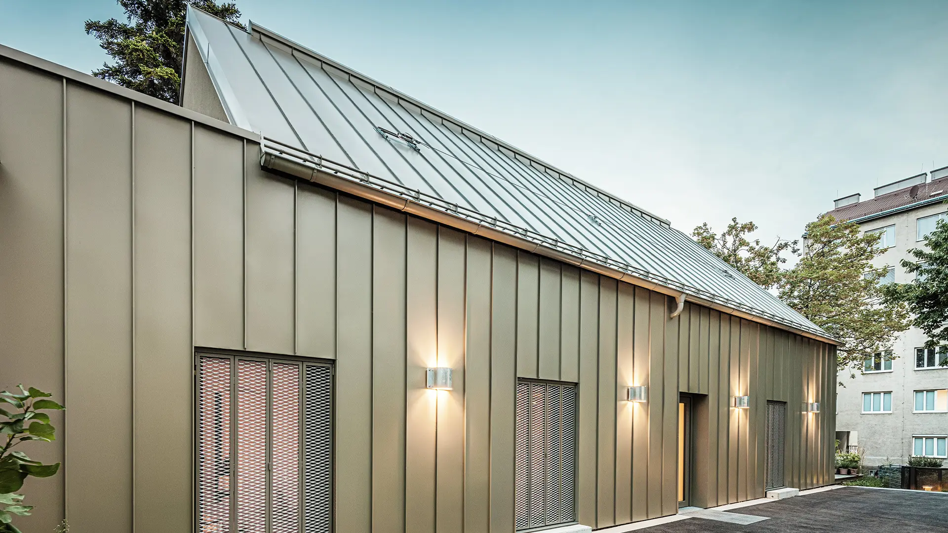 Detailní pohled na architektonický ateliér Comploj se střechnou a fasádou z drážkové krytiny PREFALZ v barvě P.10 prefa bronzové.