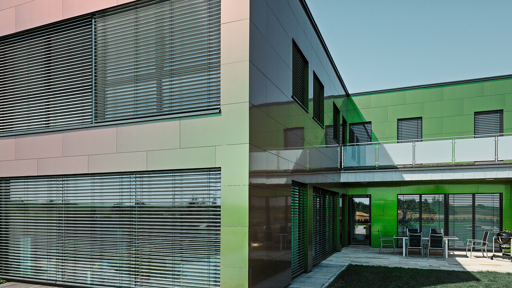 Barva fasády tohoto obytného domu z kompozitních desek se  v závislosti na dopadu světla a perpektivě pohledu mění z hnědé na zelenou nebo  tmavě fialovou   