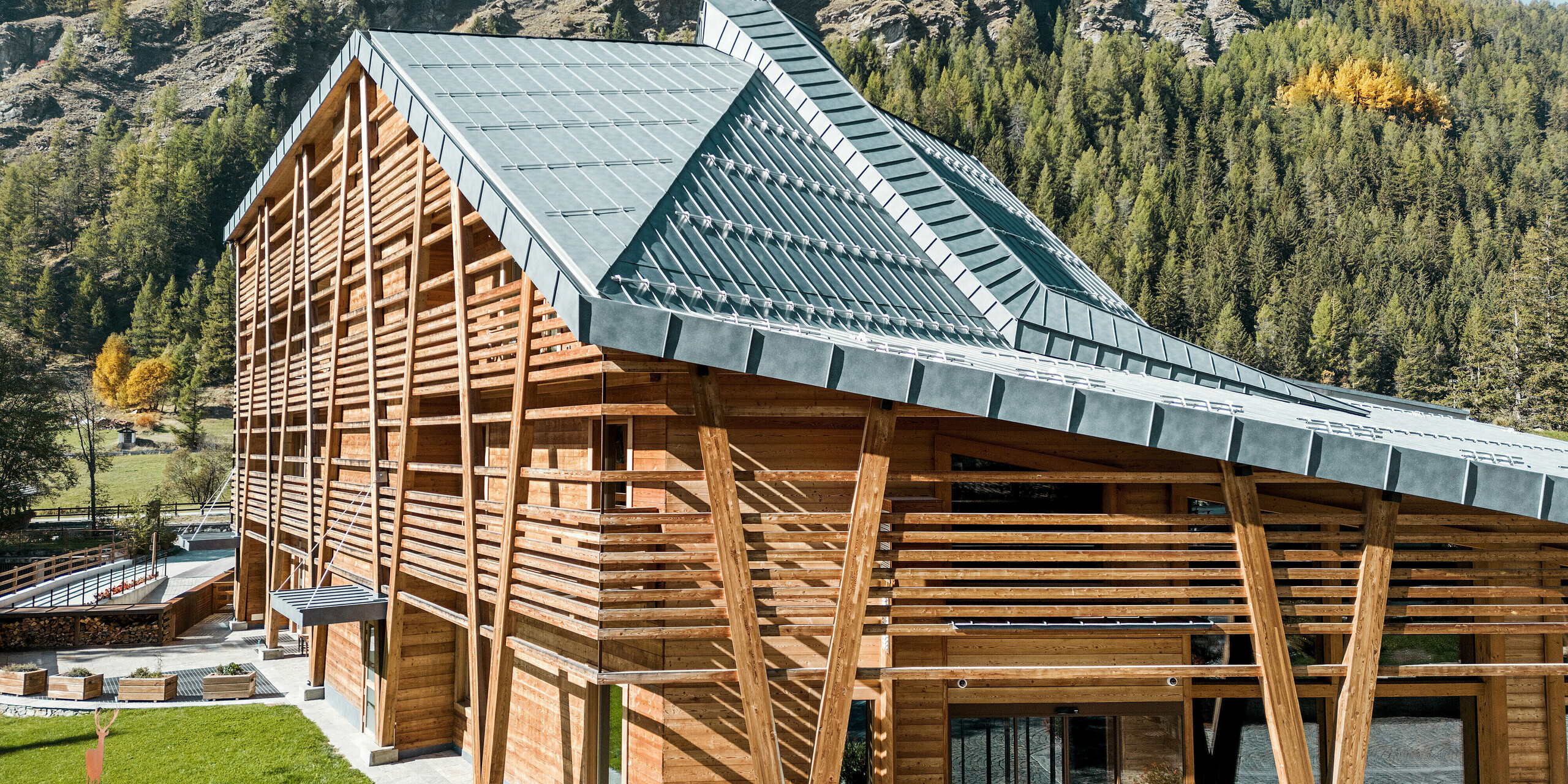 Das 5-Sterne-Öko-Hotel 'Au Charmant Petit Lac' in Champoluc, Italien, integriert sich mit seiner außergewöhnlichen Dachform und dem umgebenden Naturpanorama in eine malerische Landschaft. Das Dach, gedeckt mit PREFALZ in P.10 Steingrau, spiegelt die Farben der Natur wider und unterstreicht die Luxus-Ausrichtung des Hotels durch sein elegantes und nachhaltiges Design. Die Kombination aus natürlichem Holzbau und dem langlebigen PREFALZ Aluminium stellt eine Verbindung zwischen traditioneller Handwerkskunst und moderner Bautechnologie dar.