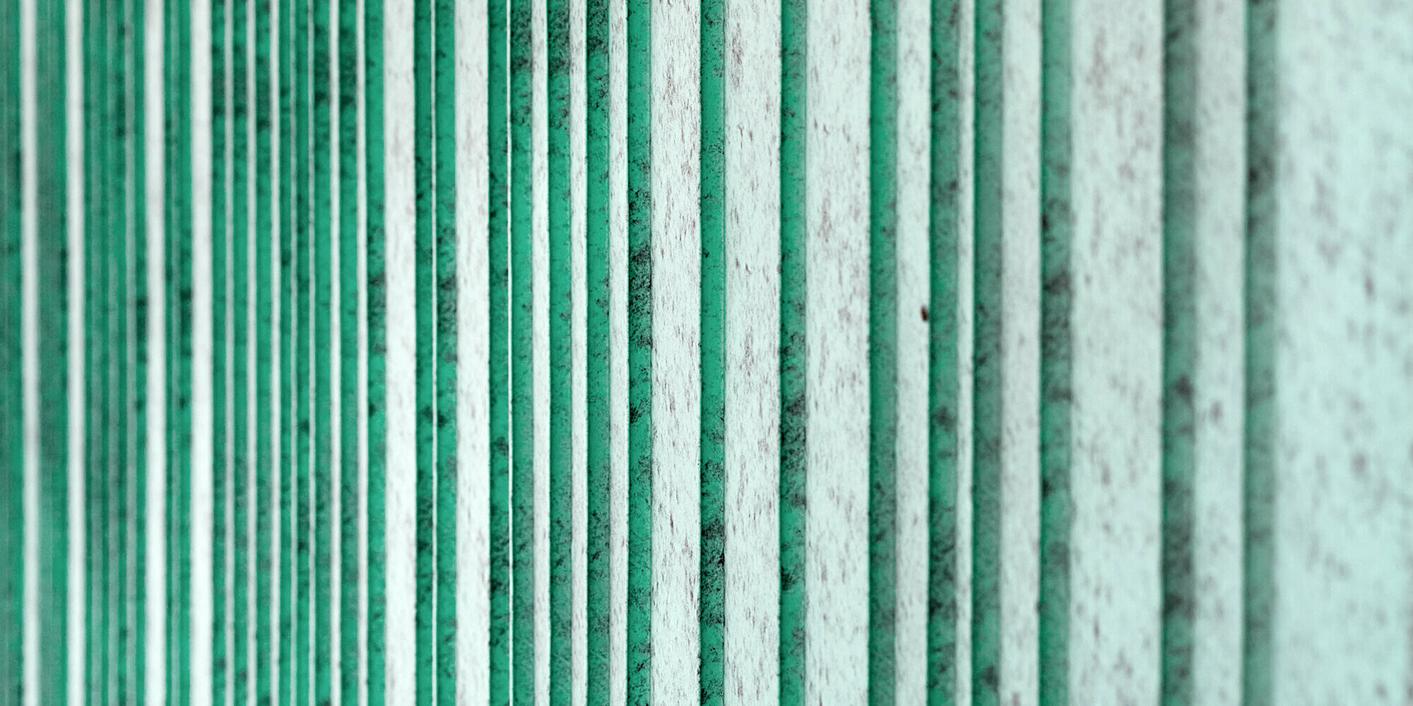 Detailní pohled na hliníkovou fasádu PREFALZ v barvě P.10 patině zelené. Fasáda je rytmizována šáry různých šířek. Barva vytváří melírovaný vzhled.