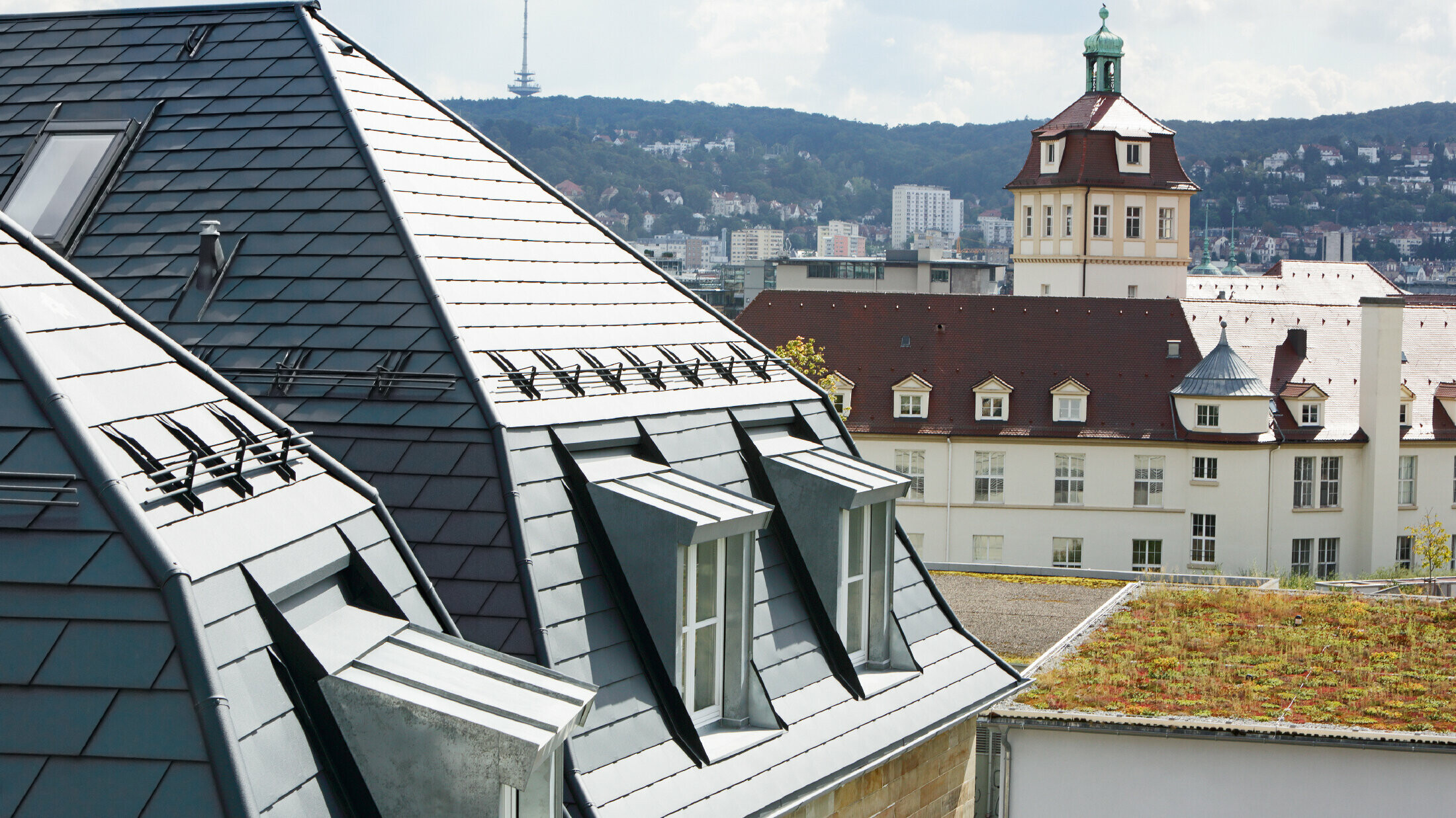 Starý měšťanský dům v Stuttgartu s lomenou střechou a mnoha vikýřovými okny, pokrytou hliníkovým PREFA falcovaným šindelem v barvě P.10 antracitové