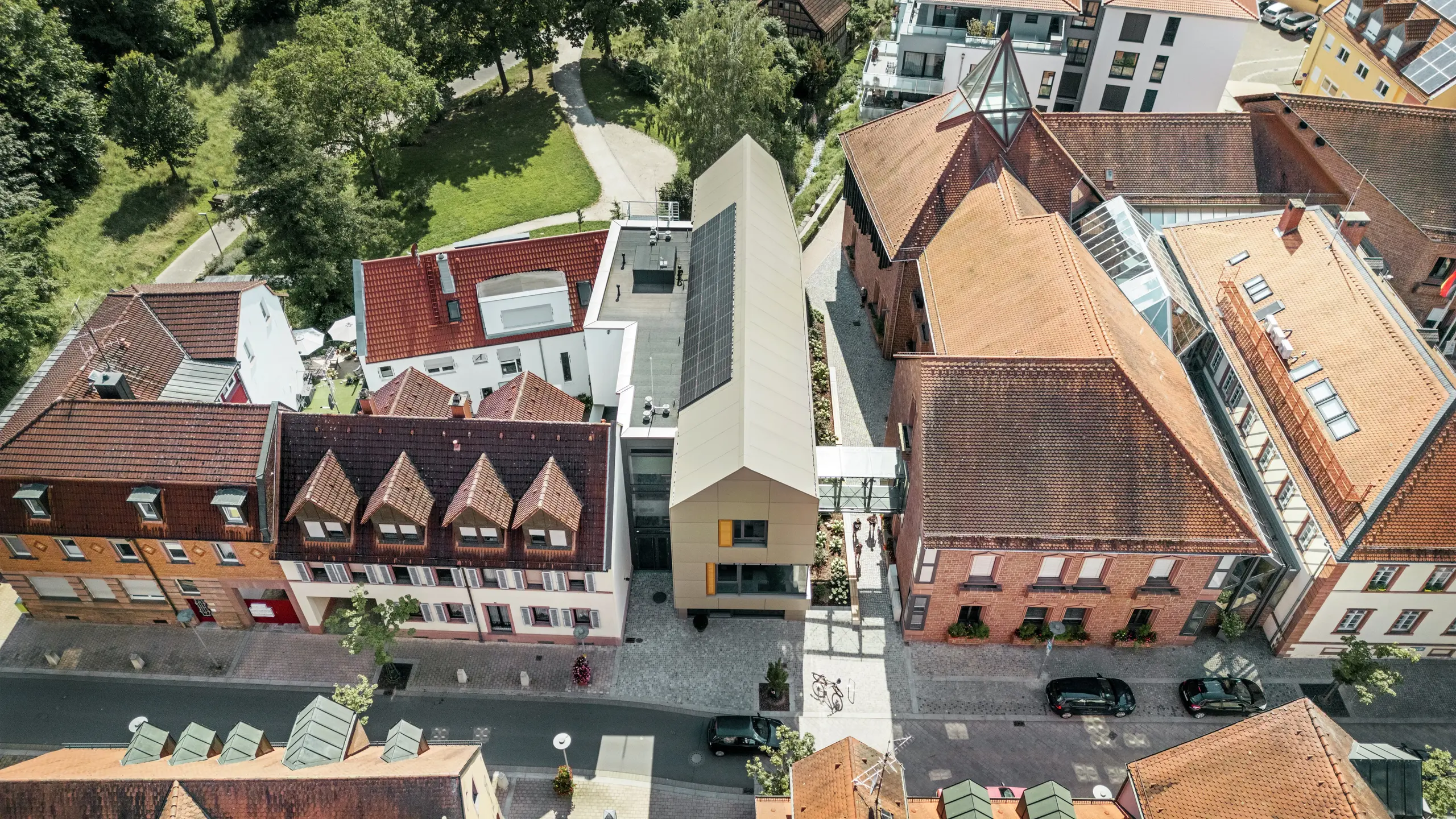 Radnice v německém Alzenau se nachází uprostřed historické městské krajiny, obklopená tradičními budovami s červenými taškovými střechami. Naproti tomu moderní radnice, jejíž fasáda je obložena hliníkovými kompozitními panely PREFABOND v elegantním bronzovém odstínu, jasně vyniká mezi sousedními klasickými budovami a harmonicky splývá s městskou krajinou.