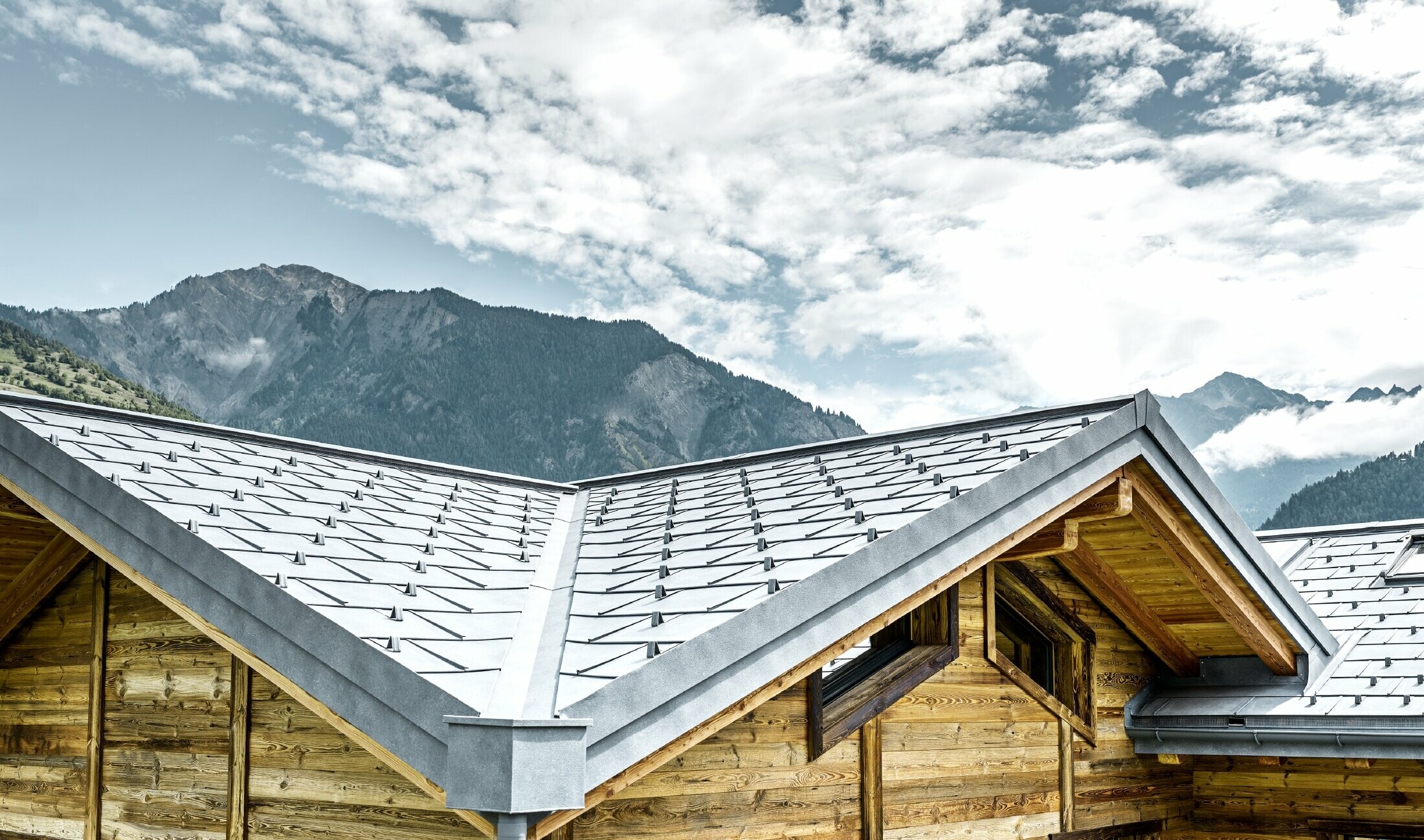 Střecha rustikální chaty ve Švýcarsku s dřevěnou fasádou a hliníkovou střechou od PREFA. Střešní panel R.16 byl je v barvě P.10 břidlicové.