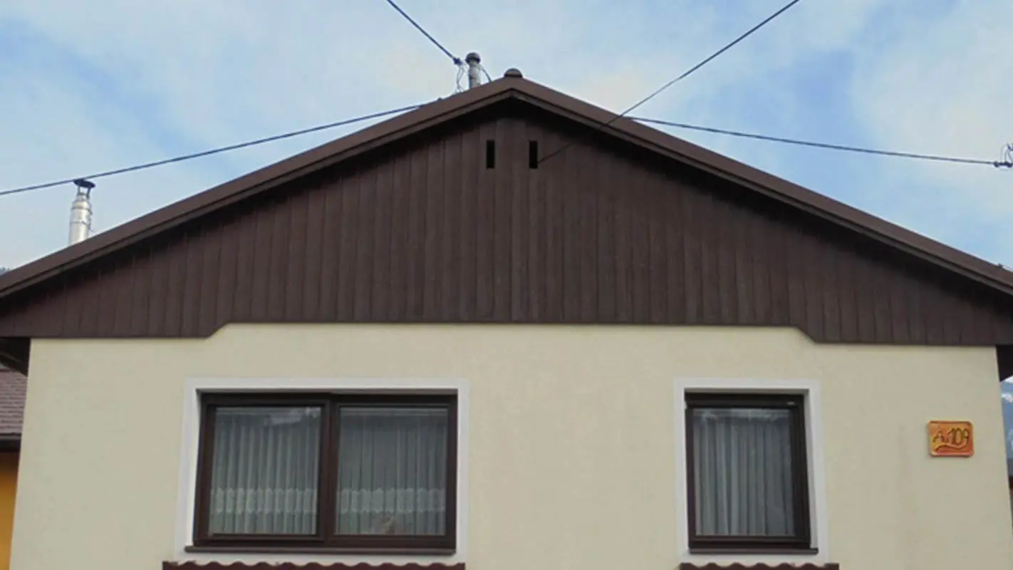Stav před sanací fasády štítu za použití PREFA Sidings, žlutá omítková fasáda, zvětralé dřevo