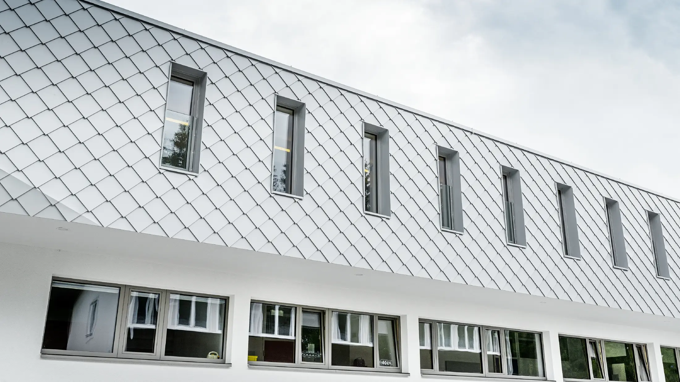 Nově postavená mateřská školka v Kaprunu s moderní PREFA hliníkovou fasádou s fasádními šablonami v prefa bílé