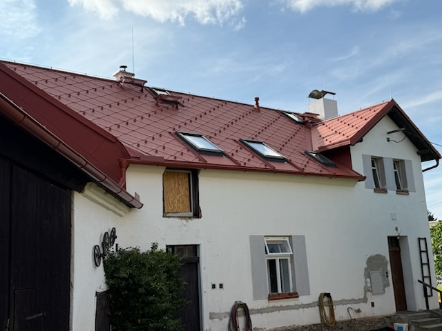 Pohled na vesnické stavení s novou střešní krytinou PREFA ve tvaru kosočtverce ve formátu 44 x 44 v barvě tmavě červené