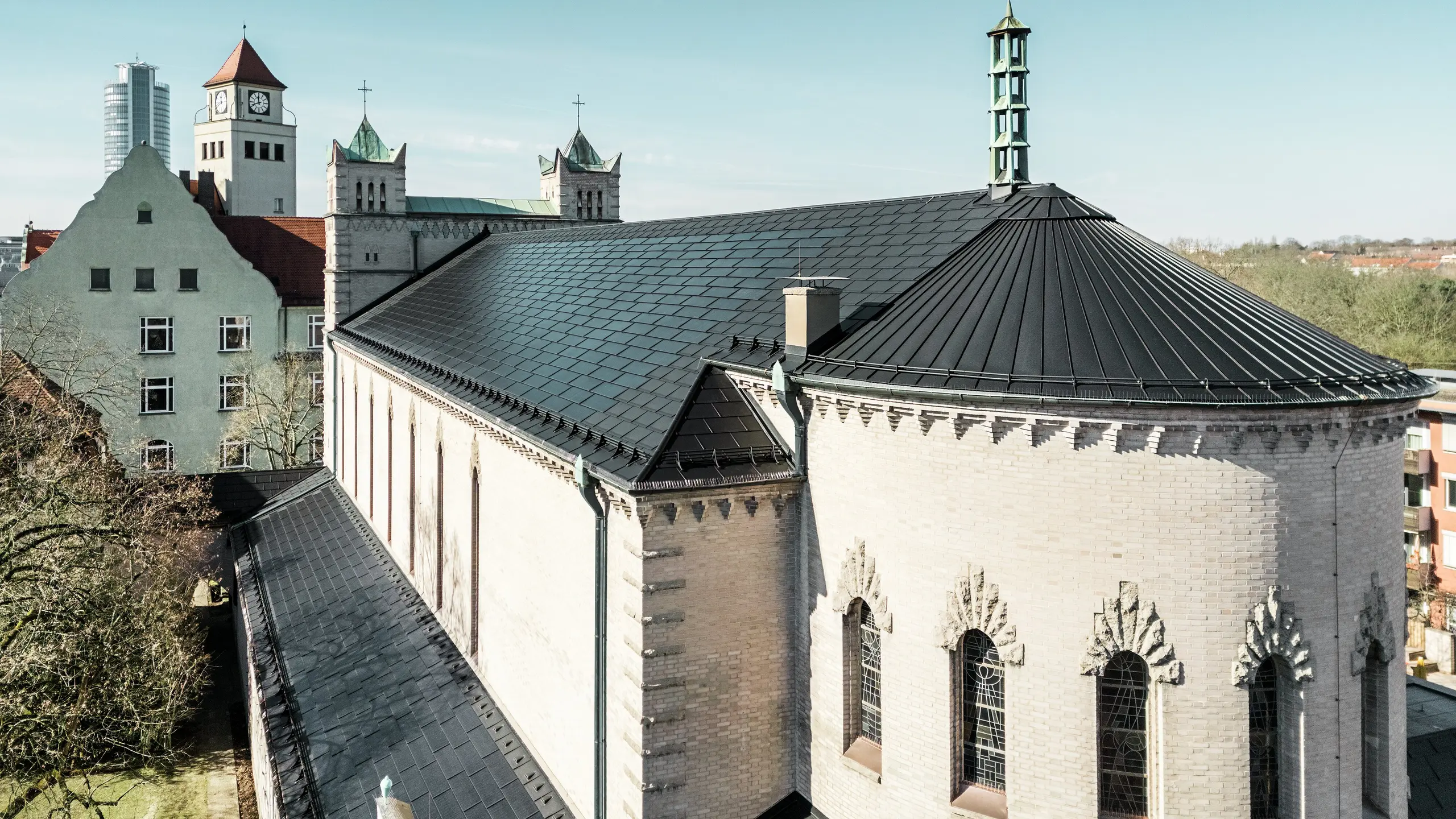 Die Sanierung der St. Karl Borromäus Kirche in Nürnberg zeigt eindrucksvoll, wie sich moderne PREFA Solardachplatten harmonisch in den Denkmalschutz integrieren lassen. Auf dem Dach ermöglichen die schwarzen Solardachplatten eine effiziente und umweltfreundliche Stromerzeugung. Nebengebäude der Kirche wurden mit der PREFA Dachplatte R.16 eingedeckt. Die beeindruckende Rundung auf der Gebäuderückseite wurde mit einer Aluminium-Stehfalzdeckung verkleidet.