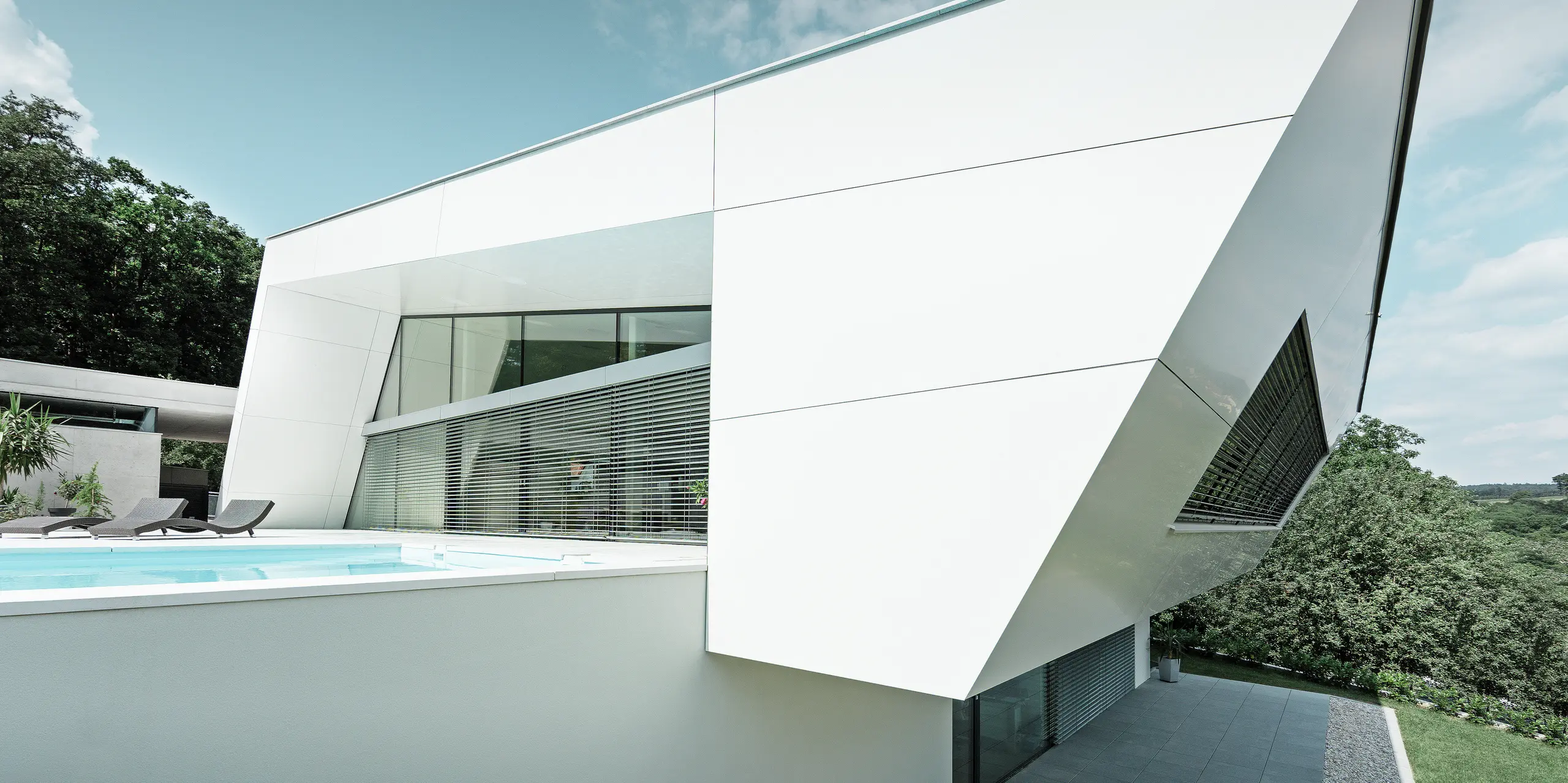 Die schrägen Linien und klaren Kanten des Wohnhauses werden durch die weiße PREFA Aluminiumfassade betont. Die PREFA Aluminium Verbundplatten in P.10 Reinweiß unterstreichen die zeitgemäße Architektur und verleihen dem Gebäude ein unverwechselbares Erscheinungsbild.