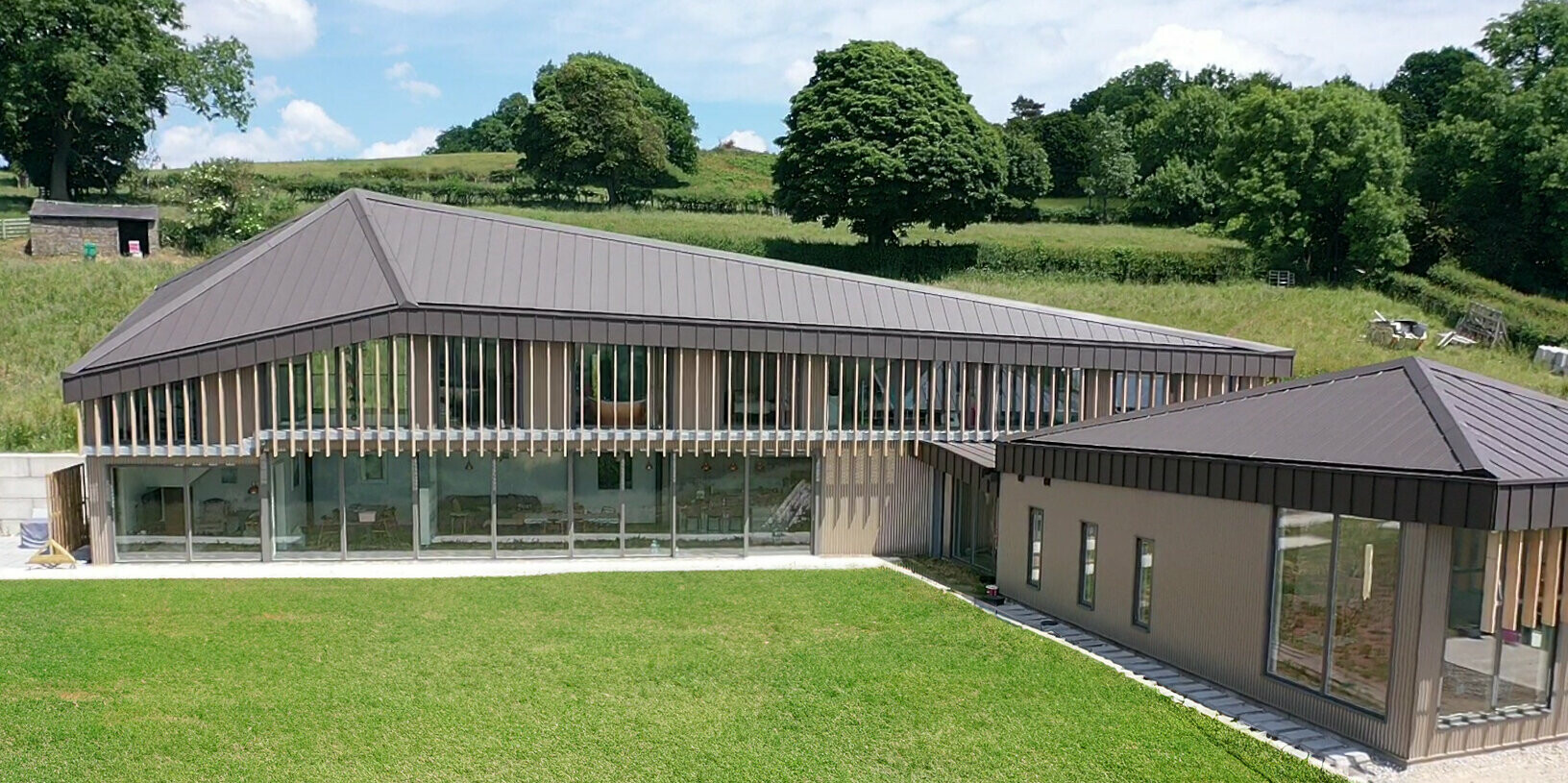 Boční pohled na longhouse s anglickým trávníkem v Derbyshire se střechou z PREFALZ v barvě P.10 tmavě hnědé